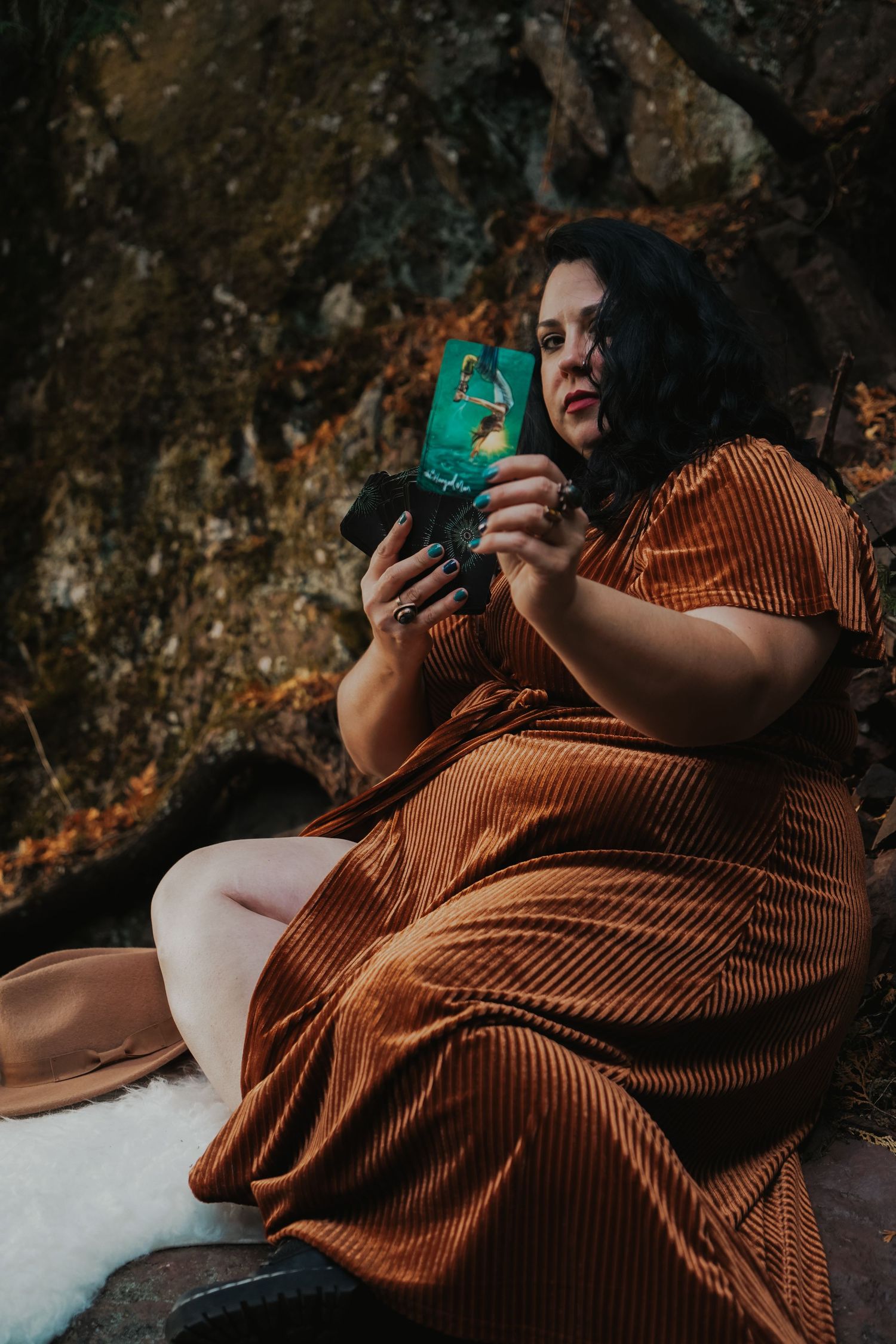 Person in rust-colored dress lying on stone surface during outdoor photo session.