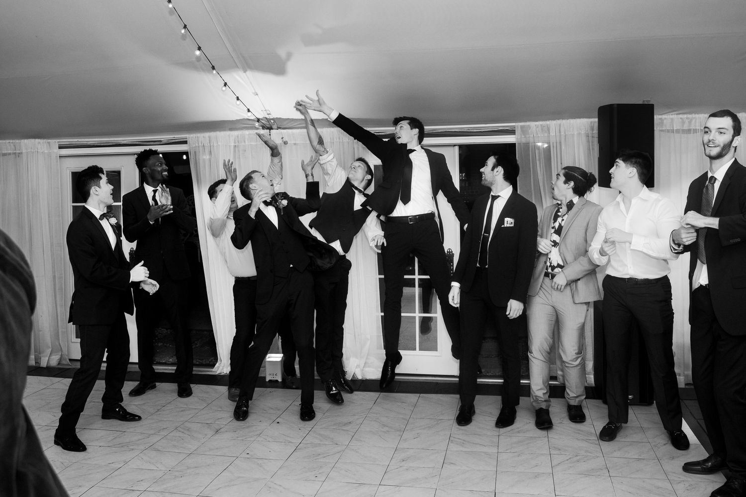 Several groomsmen leap to grab a nip of alcohol in an alternative to a bouquet toss during a wedding at Mankin Mansion in Richmond Virginia