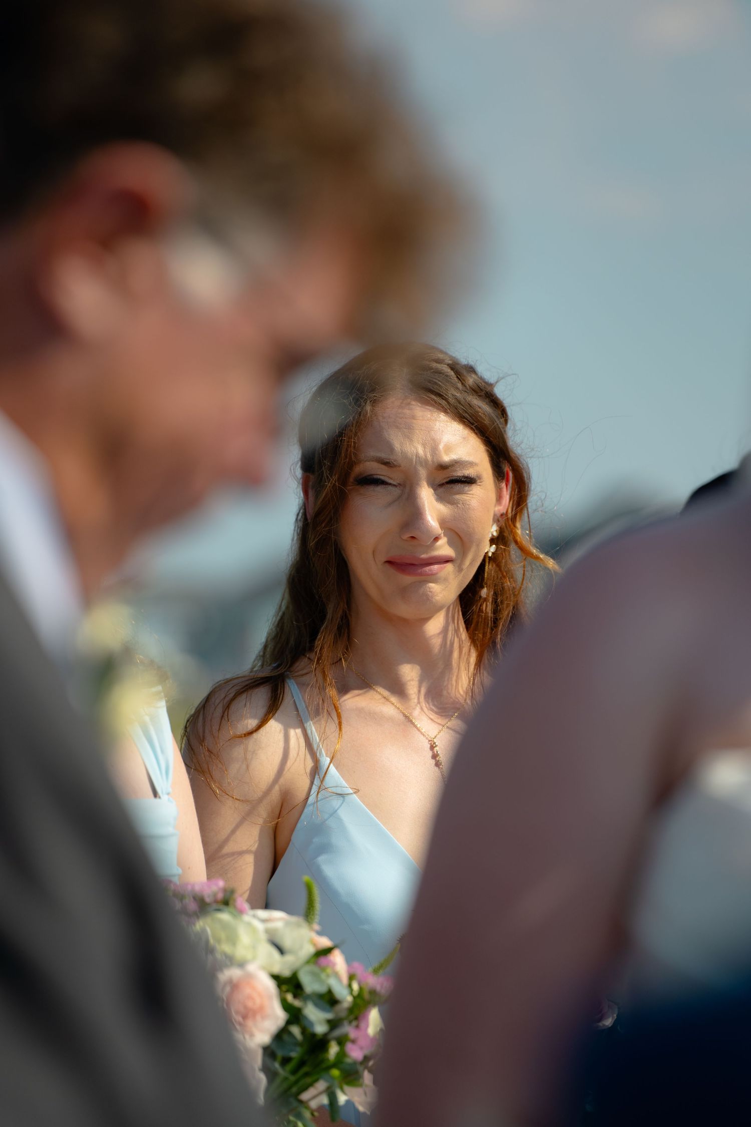 A bridesmaid tears up while the bride's father officiates his daughter's wedding on a pier in Kitty Hawk North Carolina