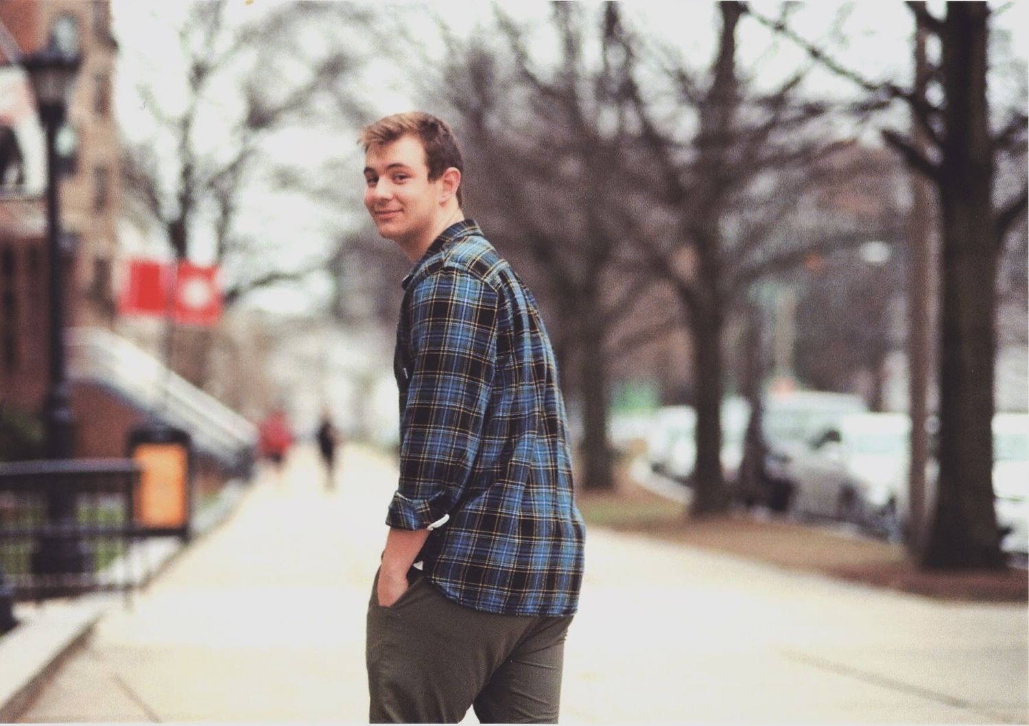 Young photo of Maine-based queer wedding and event photographer walking away from camera on the streets of Boston, MA