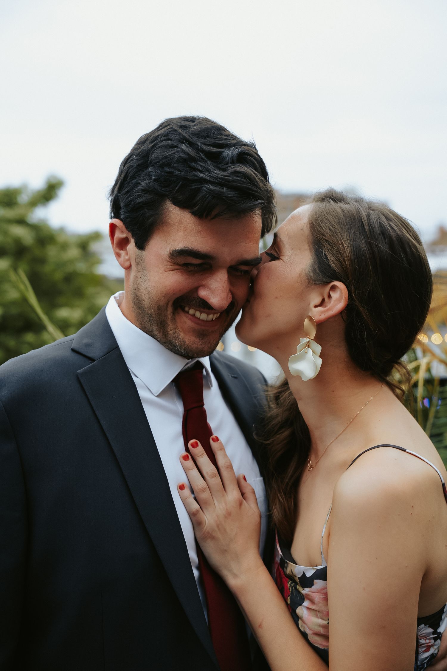 Wedding guest leans in to kiss her husband in a portrait on the rooftop of Havana 59 in downtown Richmond Virginia