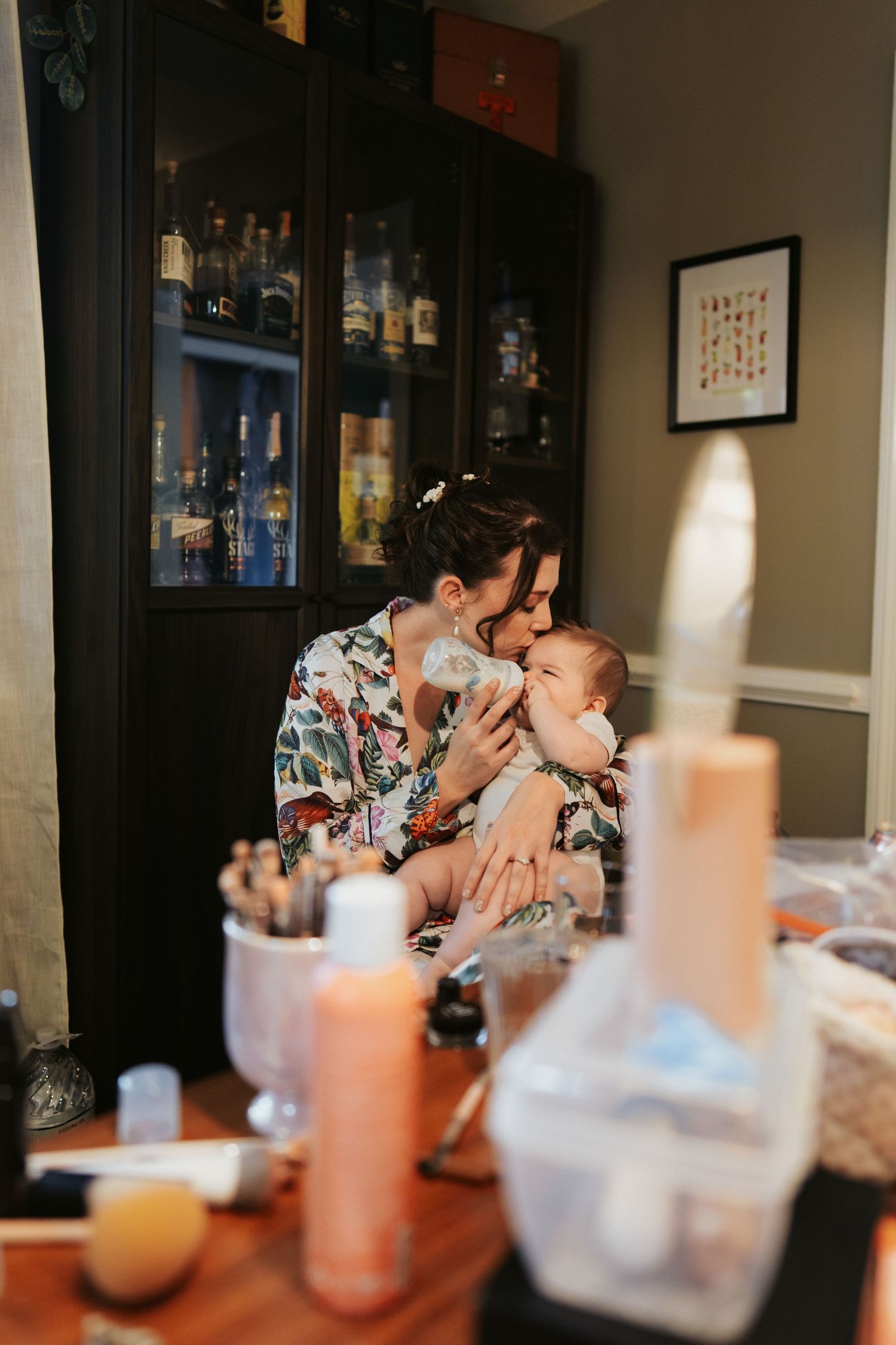 Sweet baby being fed with bottle in arms of a bridesmaid during getting ready photos