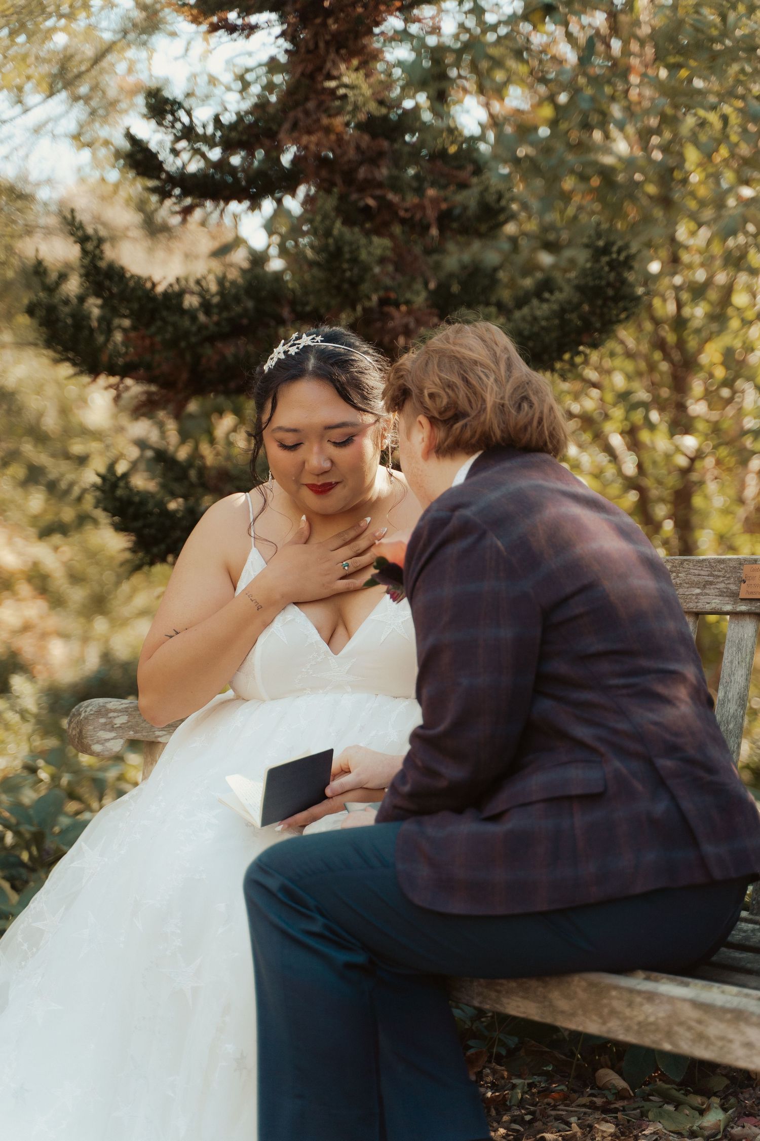 An emotional bride touches her chest to maintain composure as her bride reads her private vows during their lgbtq wedding in Maryland