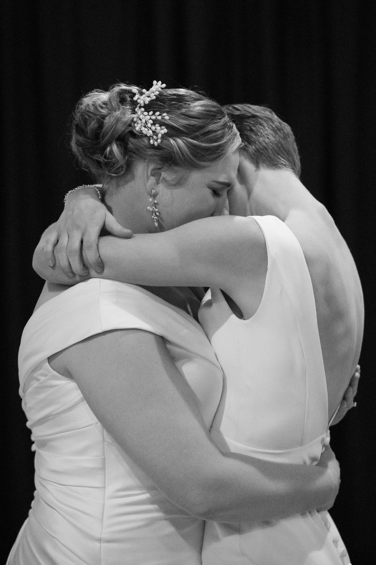 Two Virginia brides in white dresses hold each other in a close embrace just after the conclusion of their wedding ceremony