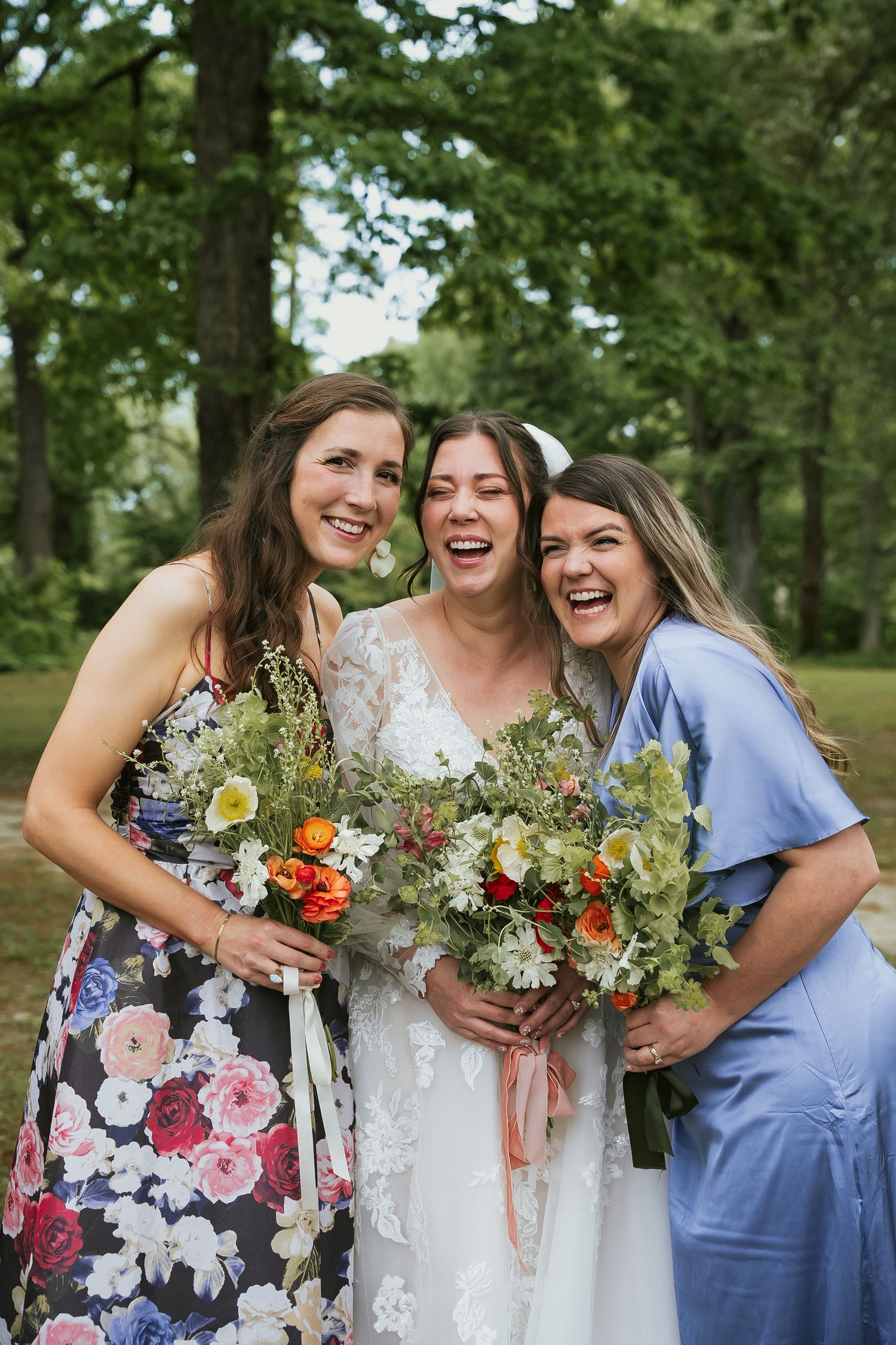 Bride and bridesmaids laugh in Bryan park with colorful bouquets in Richmond Virginia during romantic downtown wedding