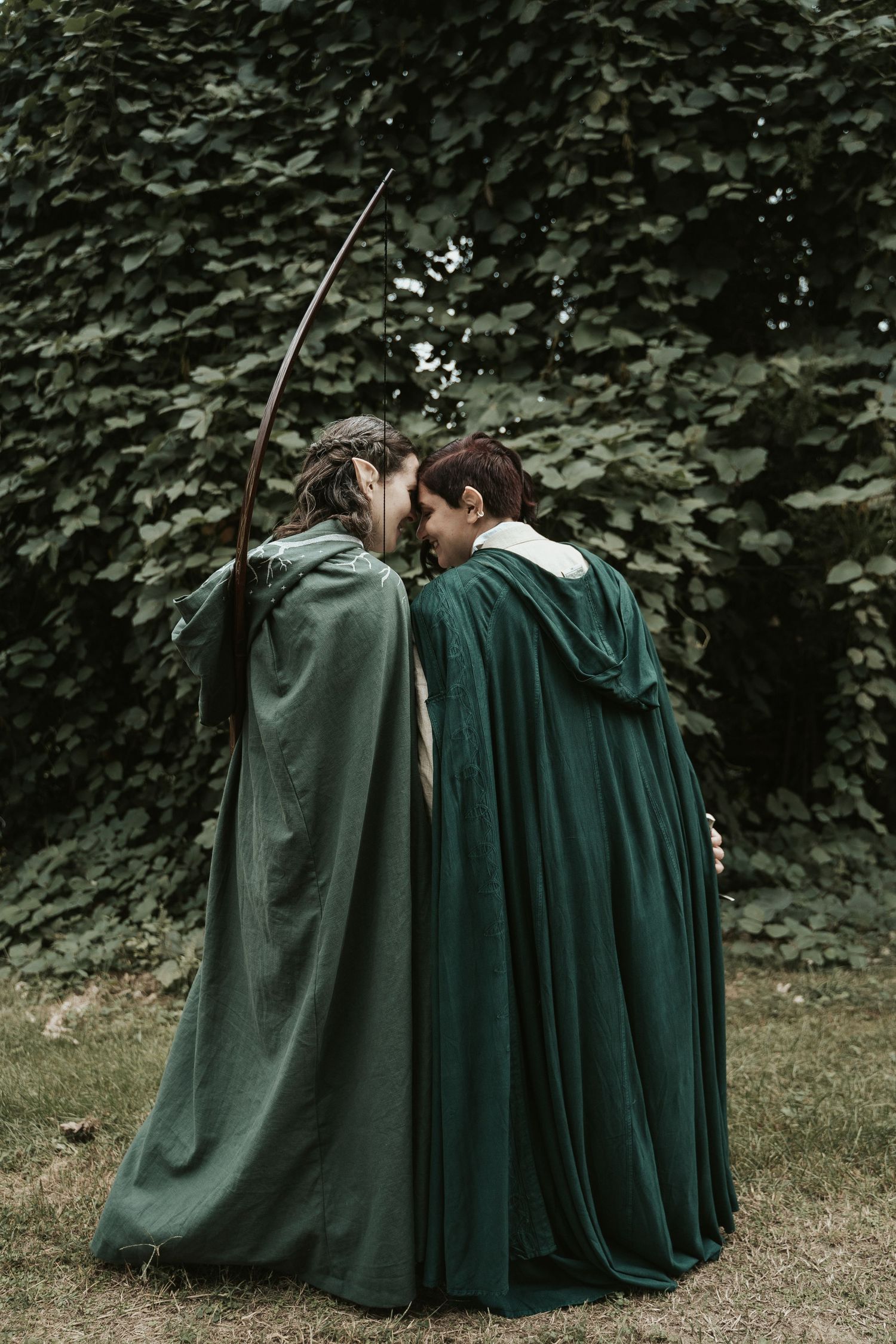 LGBTQ couple pose, placing foreheads together, in fantasy LOTR, fellowship of the ring wedding cloaks for New England Wedding Photographer