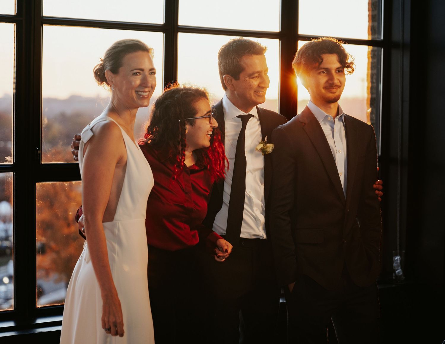 Timeless, cool aesthetic wedding photos family poses in front of window in industrial venue with fall foliage and warm colors