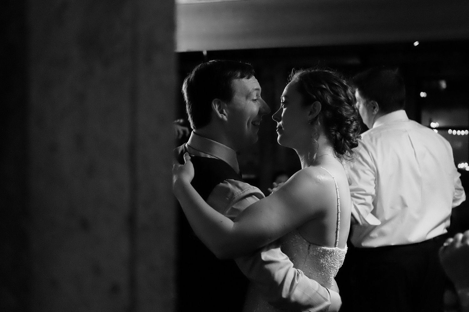 Documentary-style black and white wedding photo camera peeks out and catches couple looking at each other in intimate moment