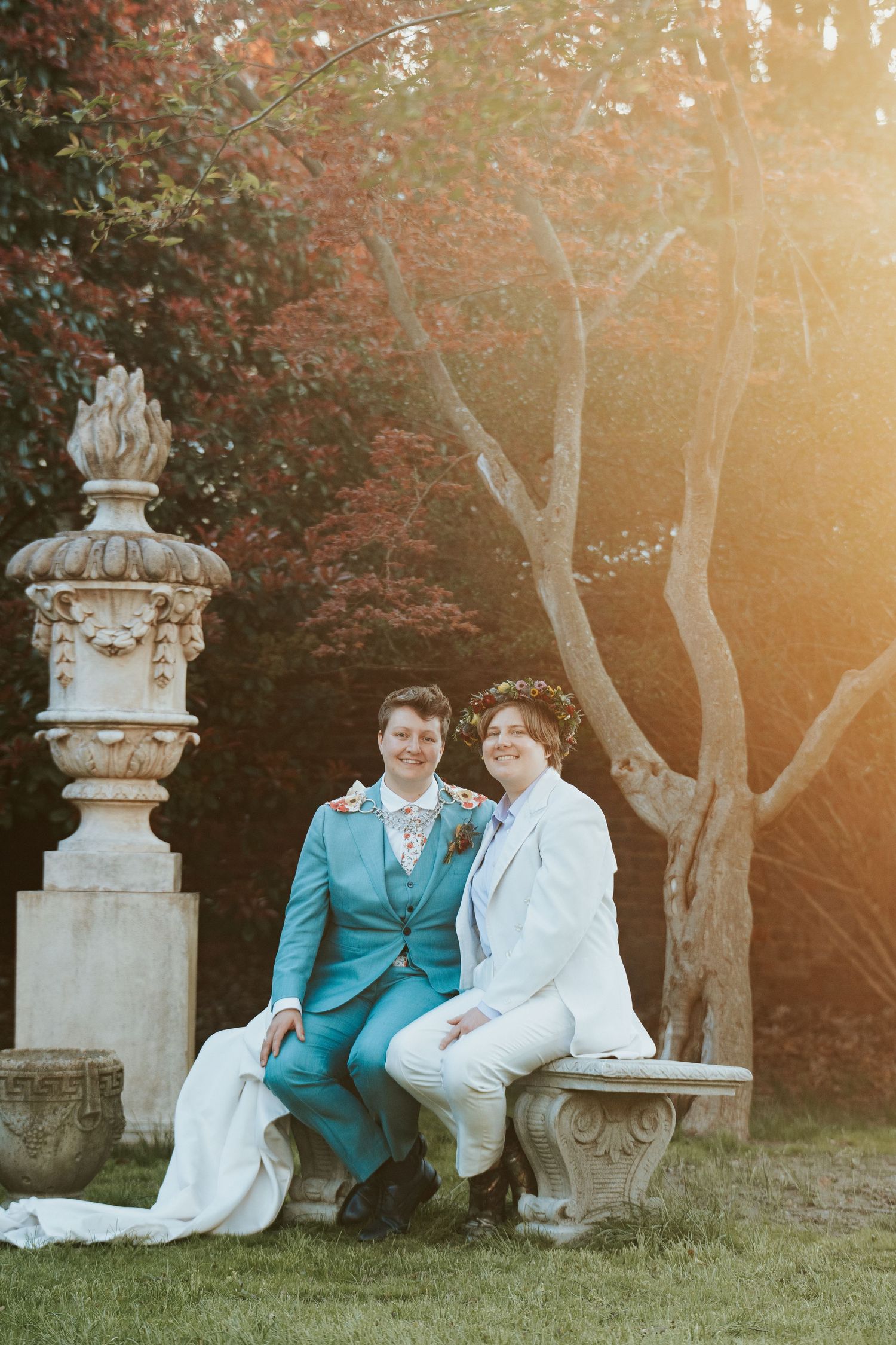 Richmond LGQTBQ brides sit in the picturesque garden of the Branch Museum as the sun sets, creating a soft yellow glow