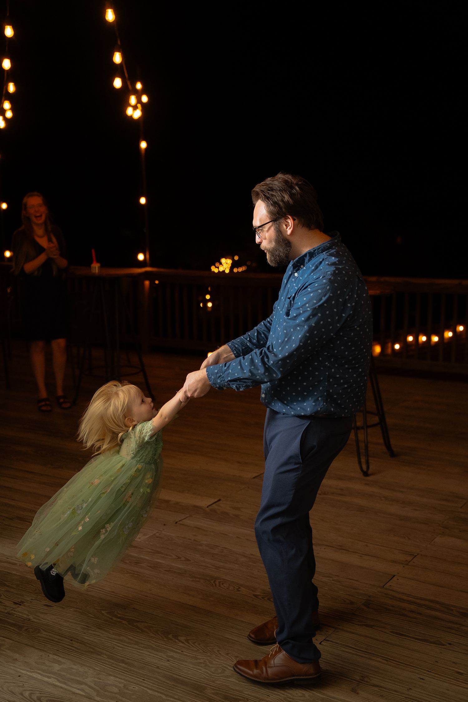 A father swings his daughter in a green dress around him during the dance party of a LGBTQ wedding at Valley Road Vineyards in Virginia