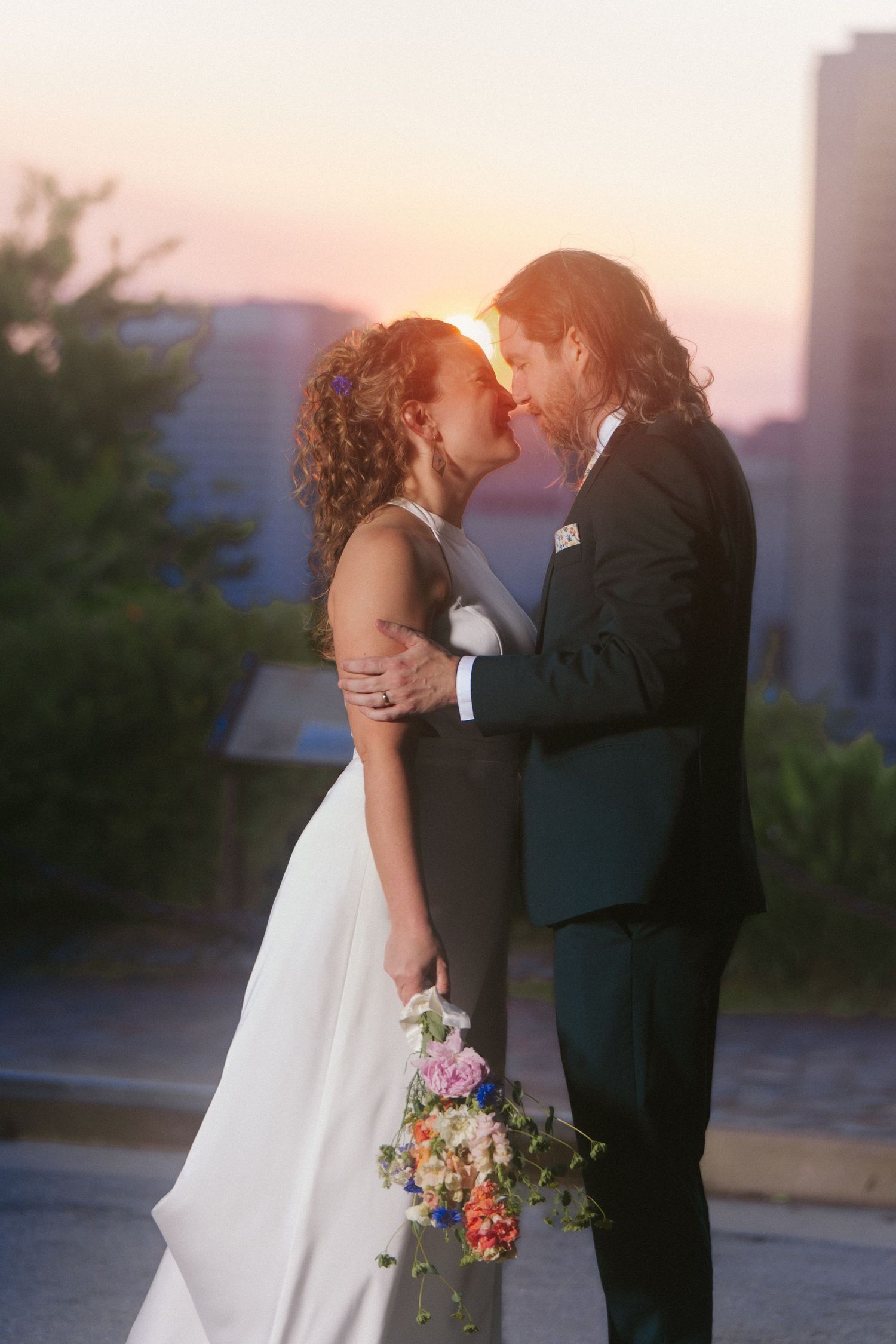 In this classic, modern wedding a bride and groom closely look into each other's eyes with the Richmond cityscape and sunset in the backgron