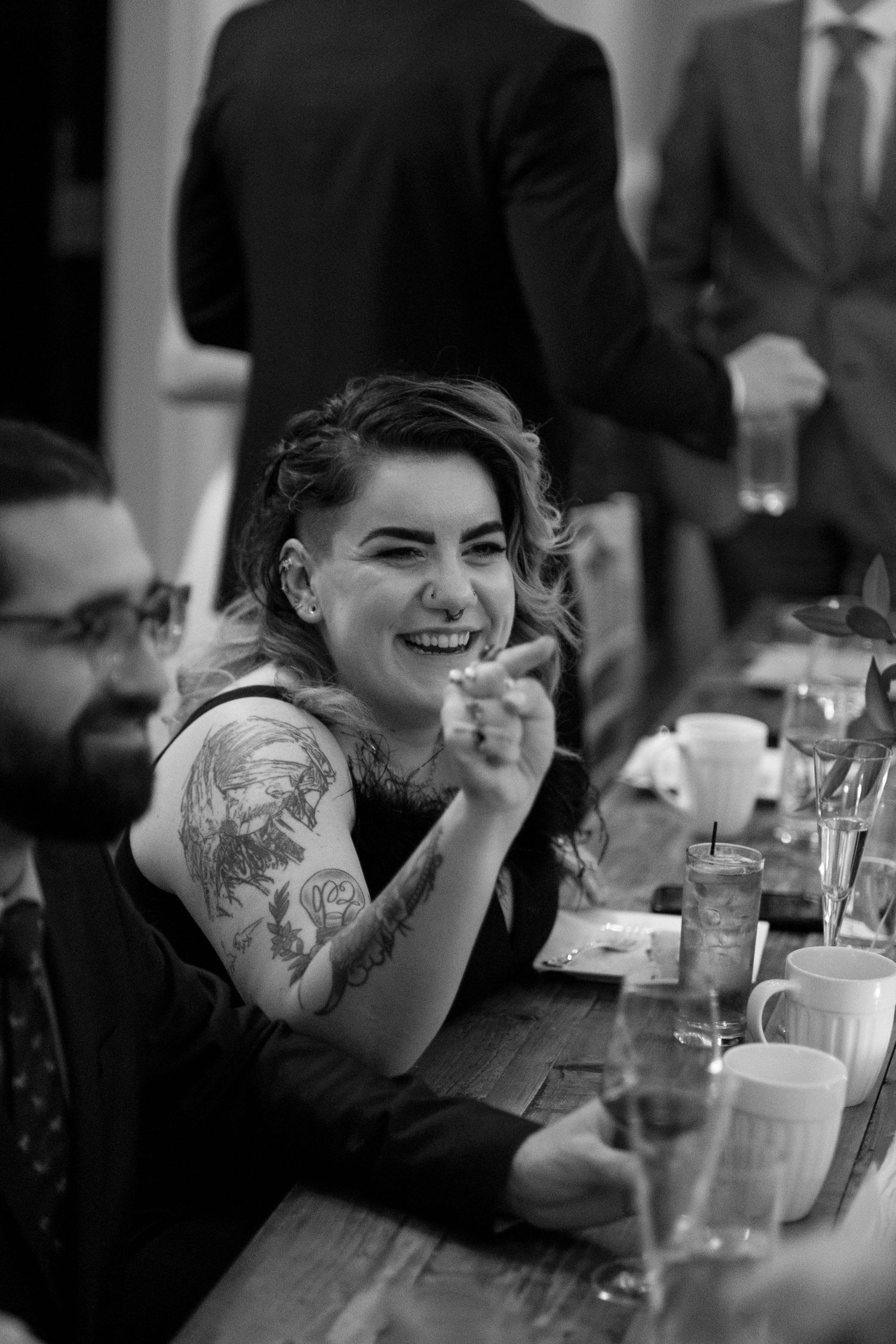 Bridesmaid laughs at the table with her family during dinner for the wedding reception of her sister at Mill at Fine Creek