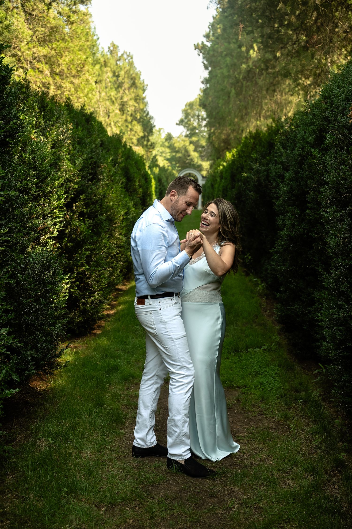 Engagement photo session in orchard rows dancing with woman in classic, chic silk dress and man in simple white pants and button down
