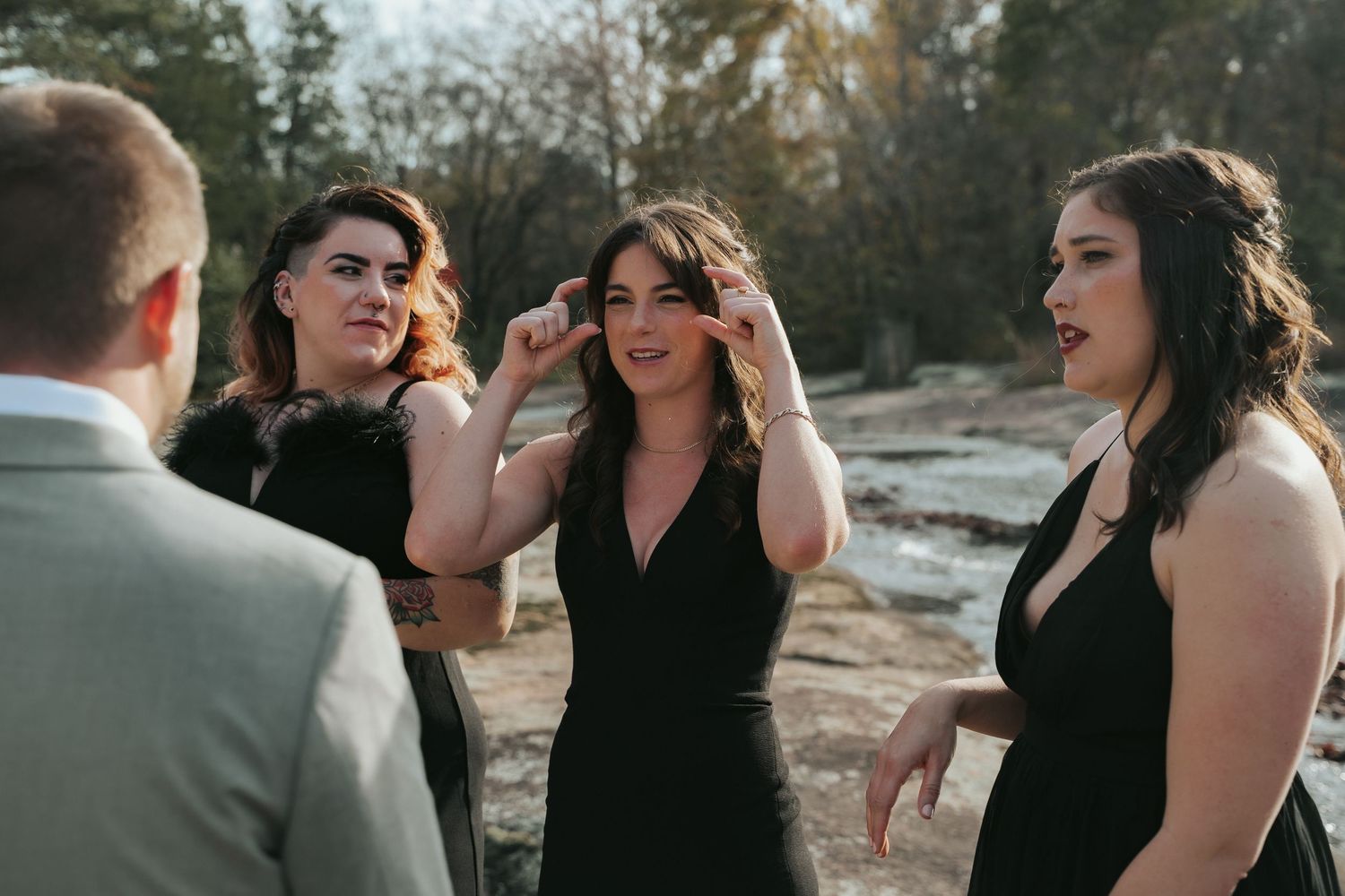 Bridesmaids talk to the groom on the rocks of a creek at Mill at Fine Creek outside Richmond Virginia