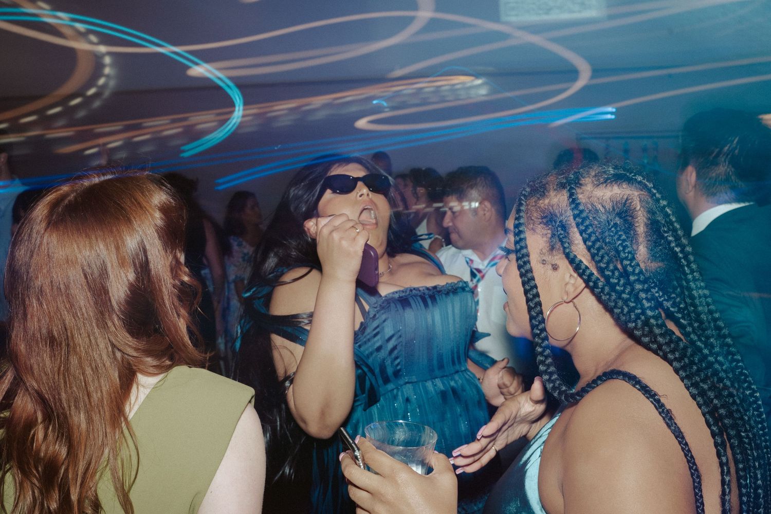 A bridesmaid wearing dark sunglasses dances hard during the reception of a gay wedding in Maryland