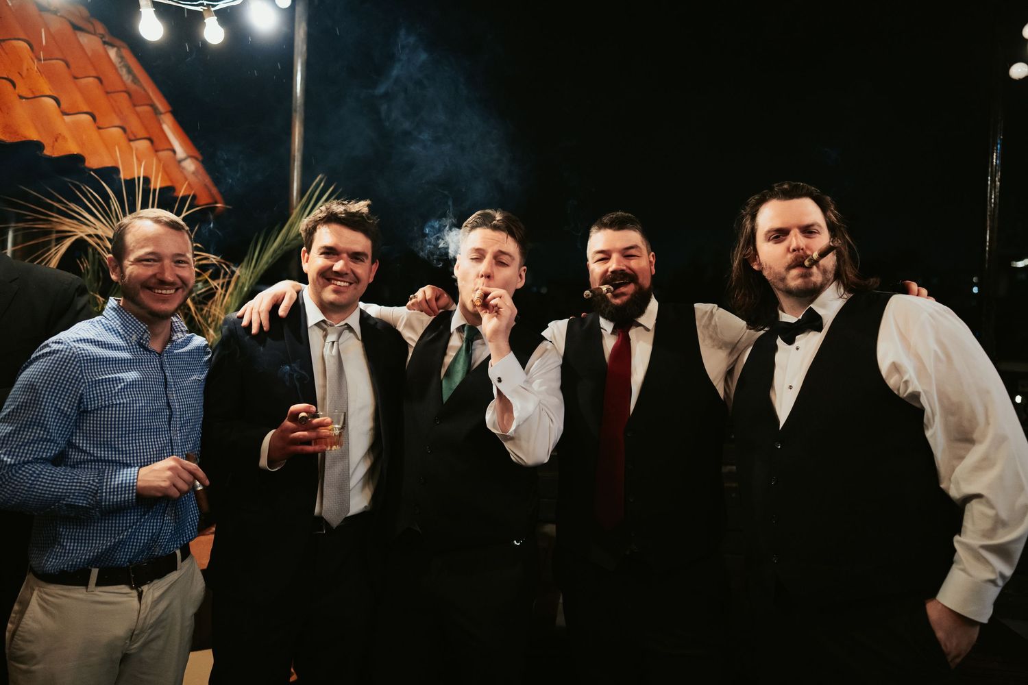 Richmond Virginia Grooms smokes cigars with his groomsmen in vests and ties on the rooftop of downtown venue Havana 59