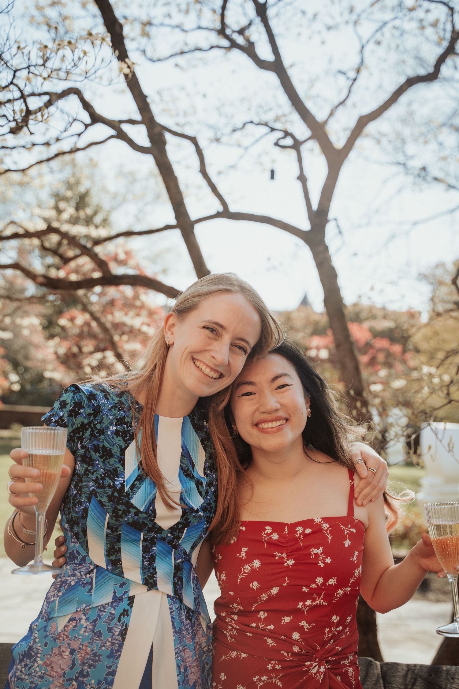 Two wedding guests in colorful dresses smile and pose together during cocktail hour at the Branch Museum in Richmond Virginia