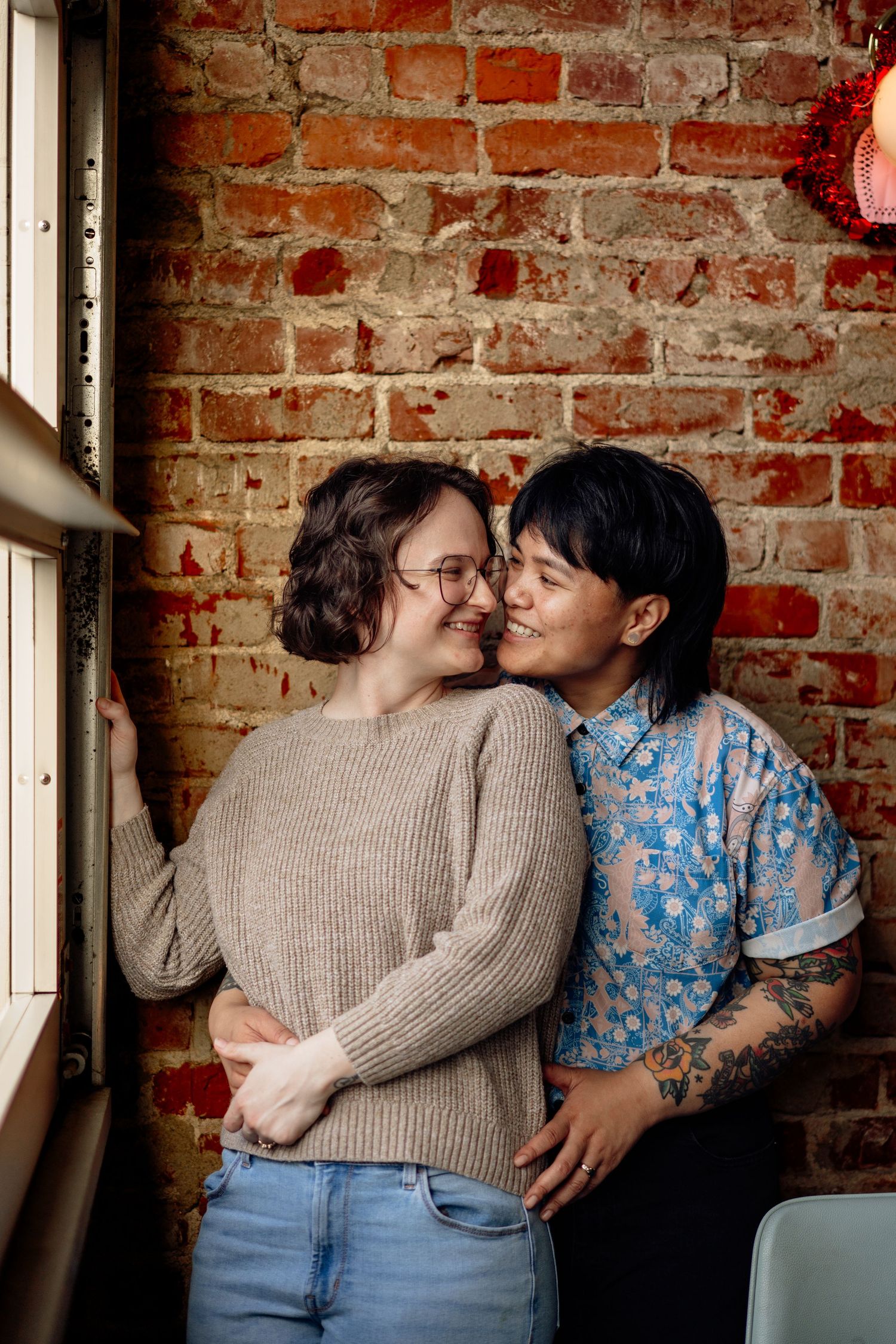 LGBT couple celebrate their engagement in photo session holding each other in casual cozy engagement session in a local diner
