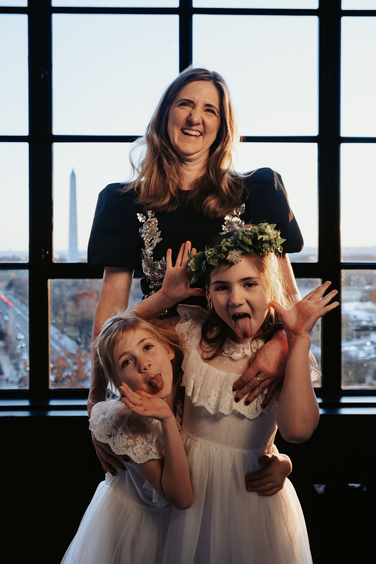 Wedding guest poses with her two daughters making silly faces in front of the Washington DC skyline at the Hotel Washington bar