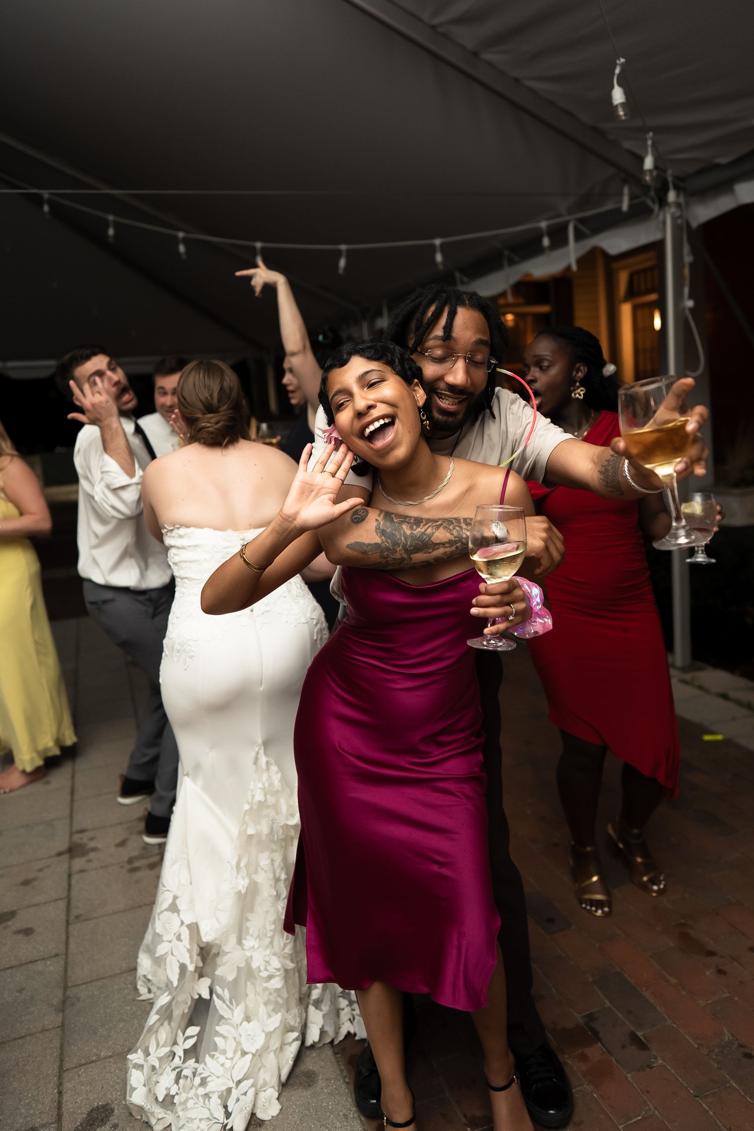 Richmond Virginia wedding guests holler and cheers their glasses on the dancefloor under the tent at Lewis Ginter Botanical Gardens