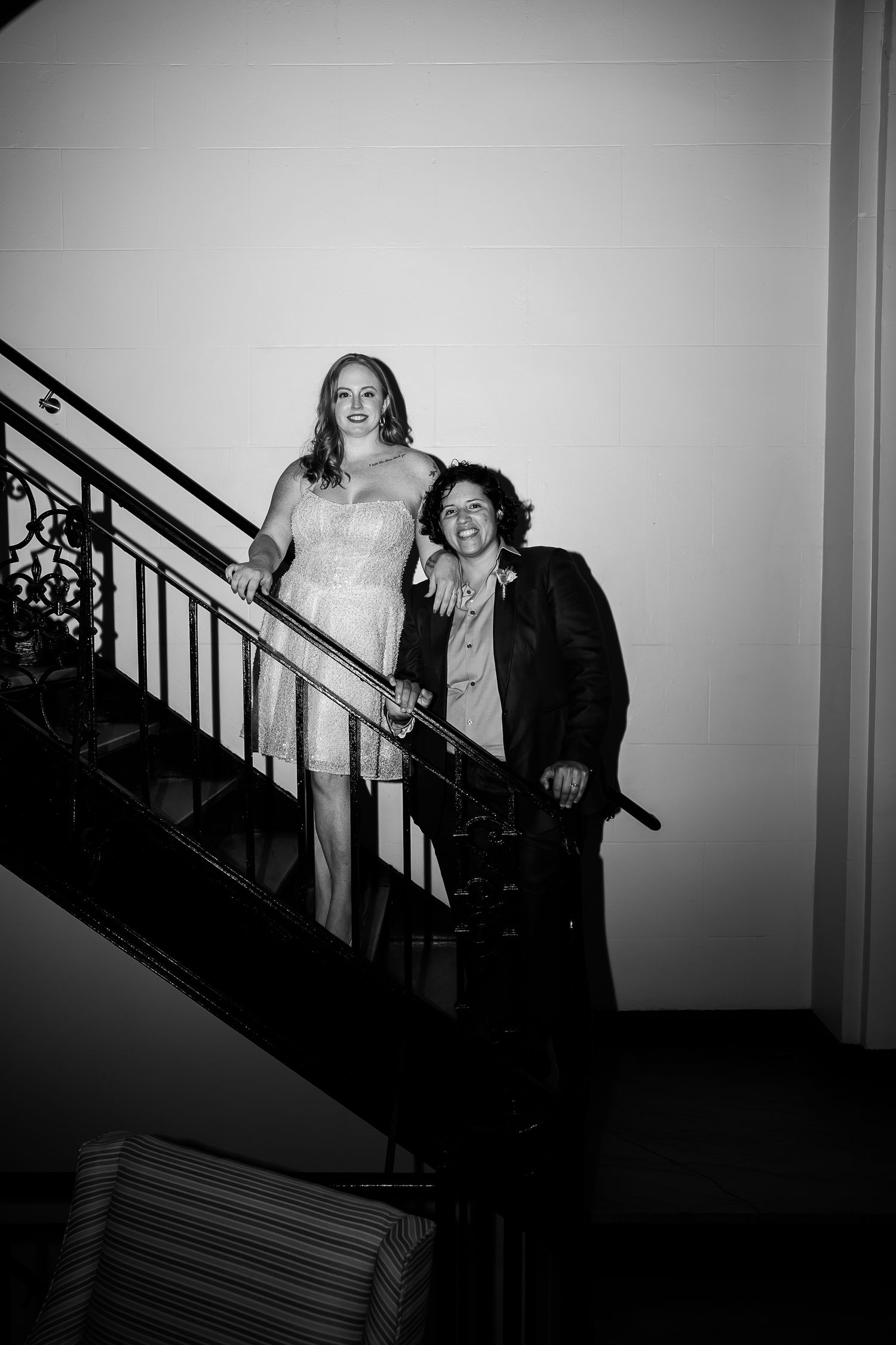Quirk modern hotel wedding with Lesbian couple in black and white whimsical retro wedding photo standing on stairs with queer photographer