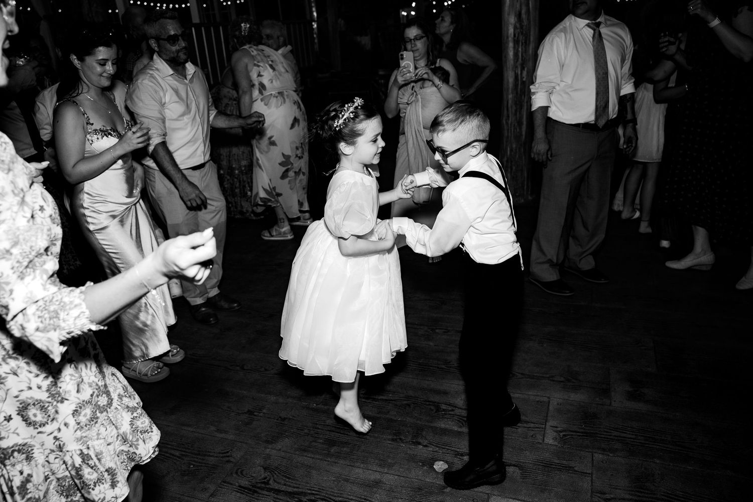 One young wedding guest jumps while dancing with her cousin on the dancefloor of a wedding at Avonlea Farms outside Richmond Virginia