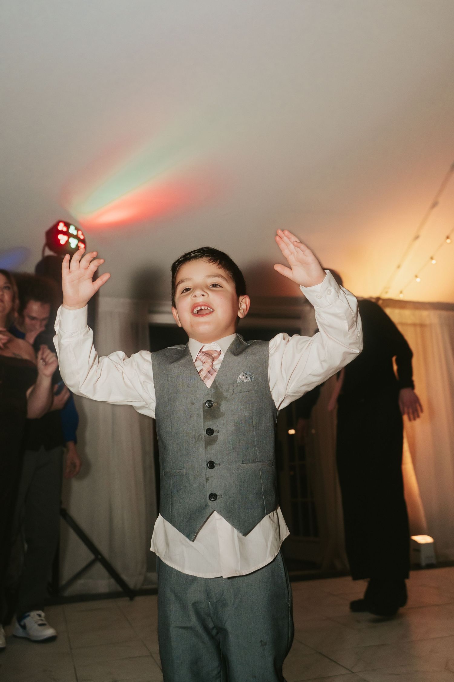 Young wedding guest raises his hands up on the dancefloor of a reception at Mankin Mansion outside Richmond Virginia