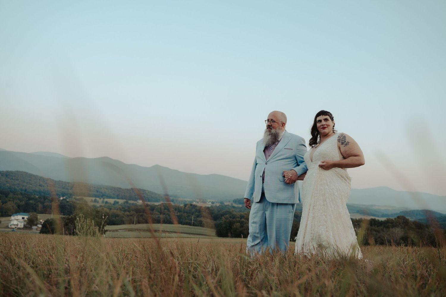 Bride and groom walk an evening ridge in sunset portrait in the blue ridge mountains of Virginia