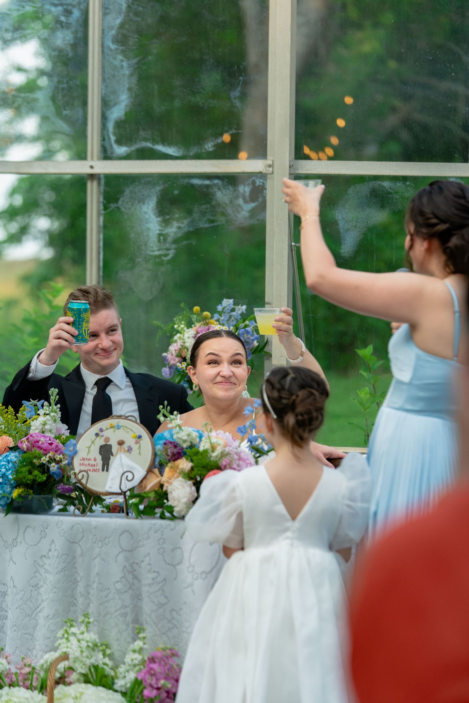 Virginia bride and groom raise their glasses after the bride's sister and niece toast them in a greenhouse at Avonlea Farms