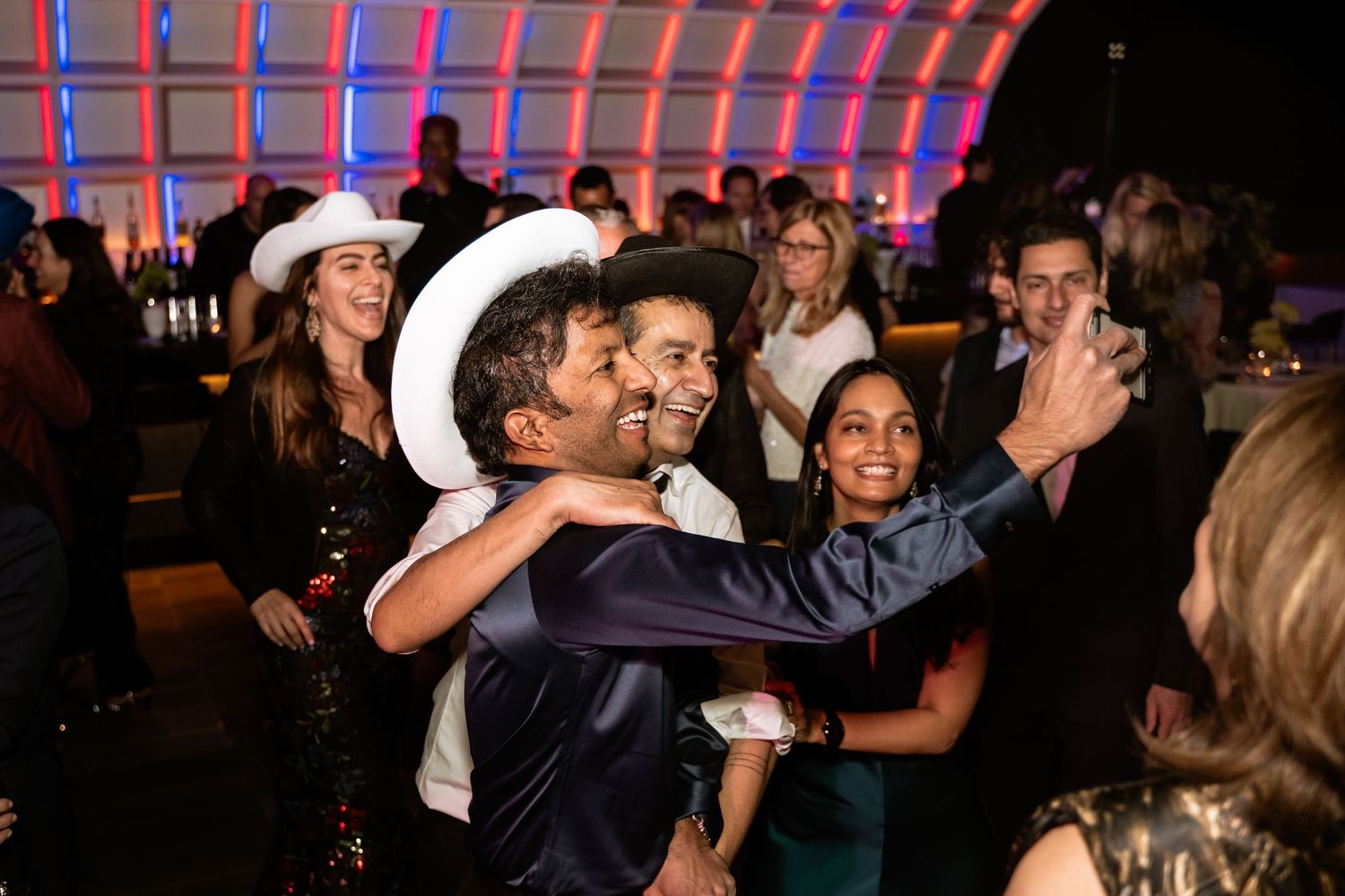 A Washington DC groom smiles for a selfie with his guest in a cowboy hat during his wedding at Hotel Washington