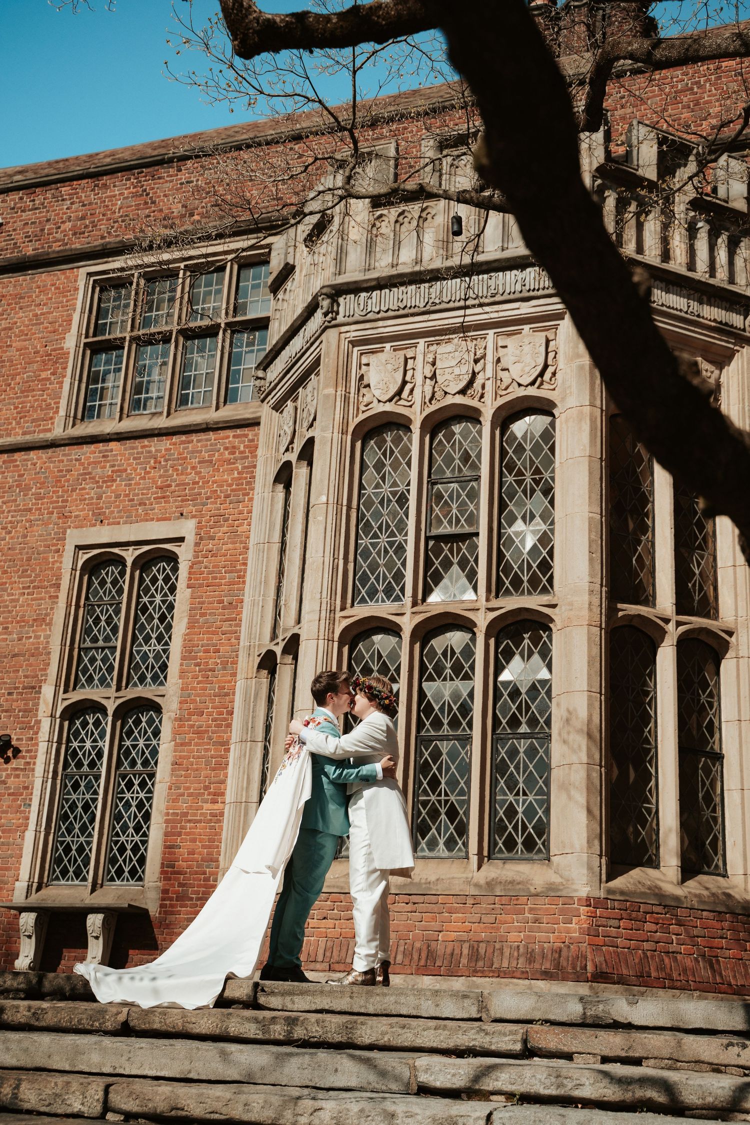 Queer wedding celebrants kiss wearing cape and in fantasy whimsical aesthetic in front of historical architectural museum in Richmond VA