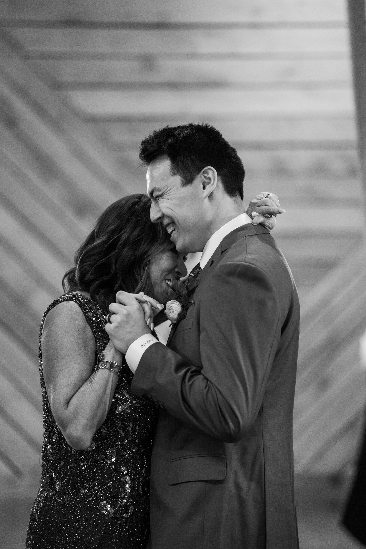 Groom smiles as his mother leans in to him during their mother son dance during a wedding reception in the Blue Ridge Mountains