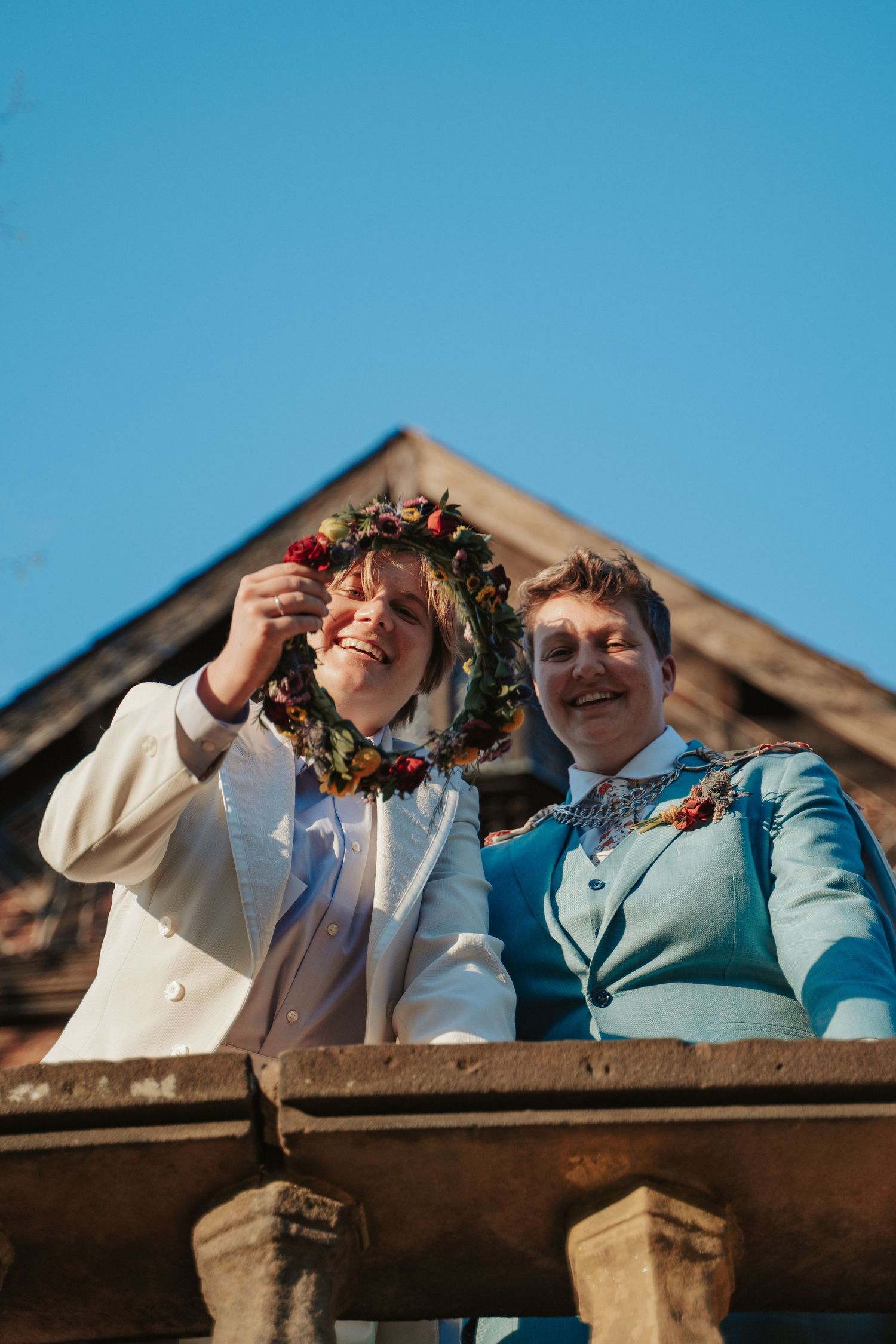 LGBT couple wearing suits look down at the camera from a balcony in a fantasy wedding at the branch museum in Richmond Virginia