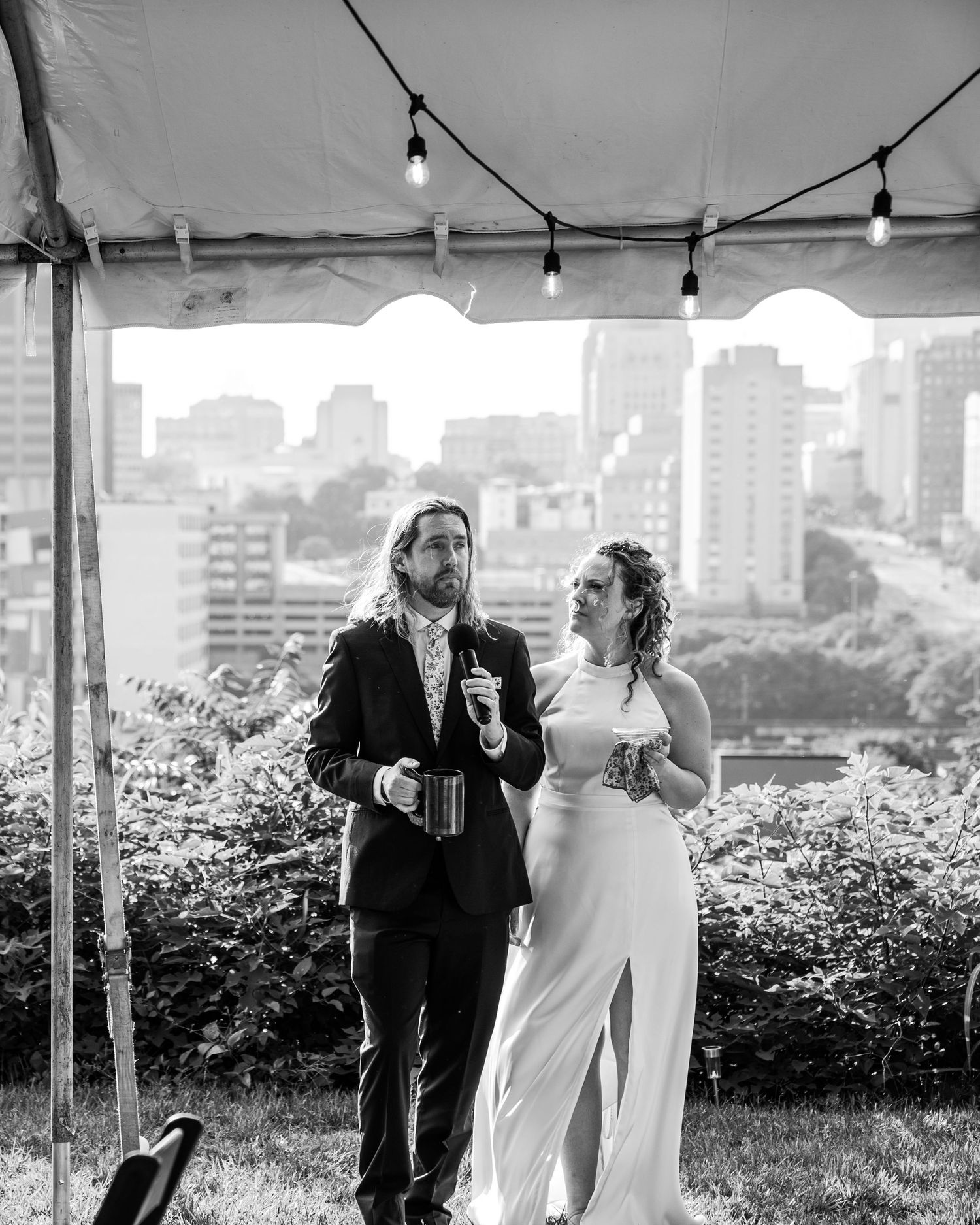Bride and groom welcome their guests in front of the Richmond Virginia skyline under a tent at the childsavers building