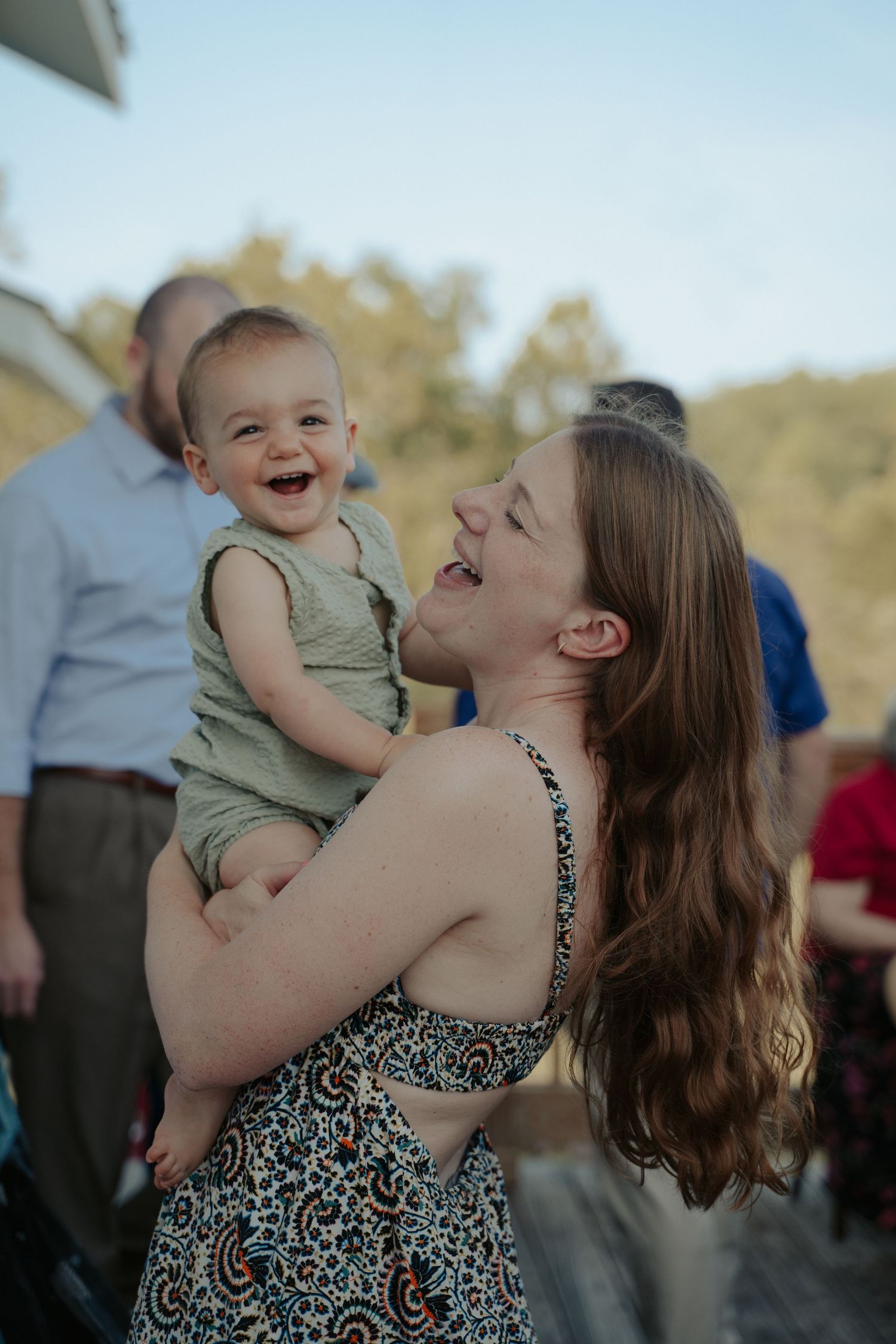 A wedding guest holds her smiling toddler during cocktail hour at a Shenandoah Virginia event