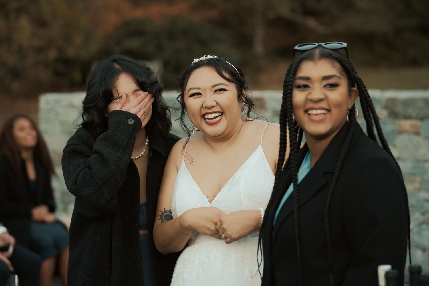 LGBTQ bride laughs with her wedding party during cocktail hour documentary style photograph at garden party wedding in Maryland