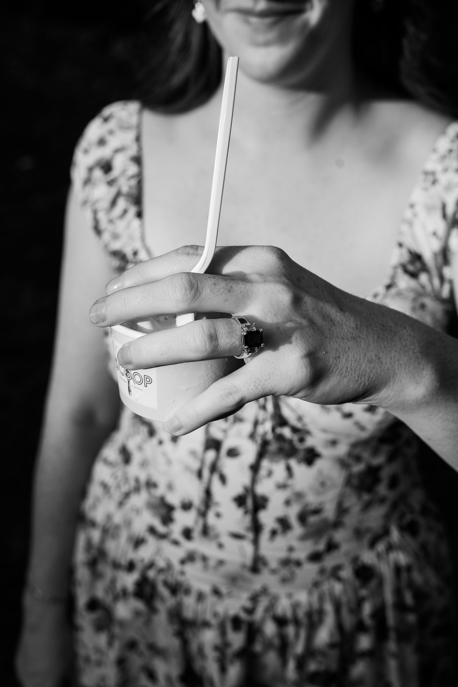 Black and white retro engagement shoot featuring a woman in a floral patterned dress holding ice cream in the center of the picture