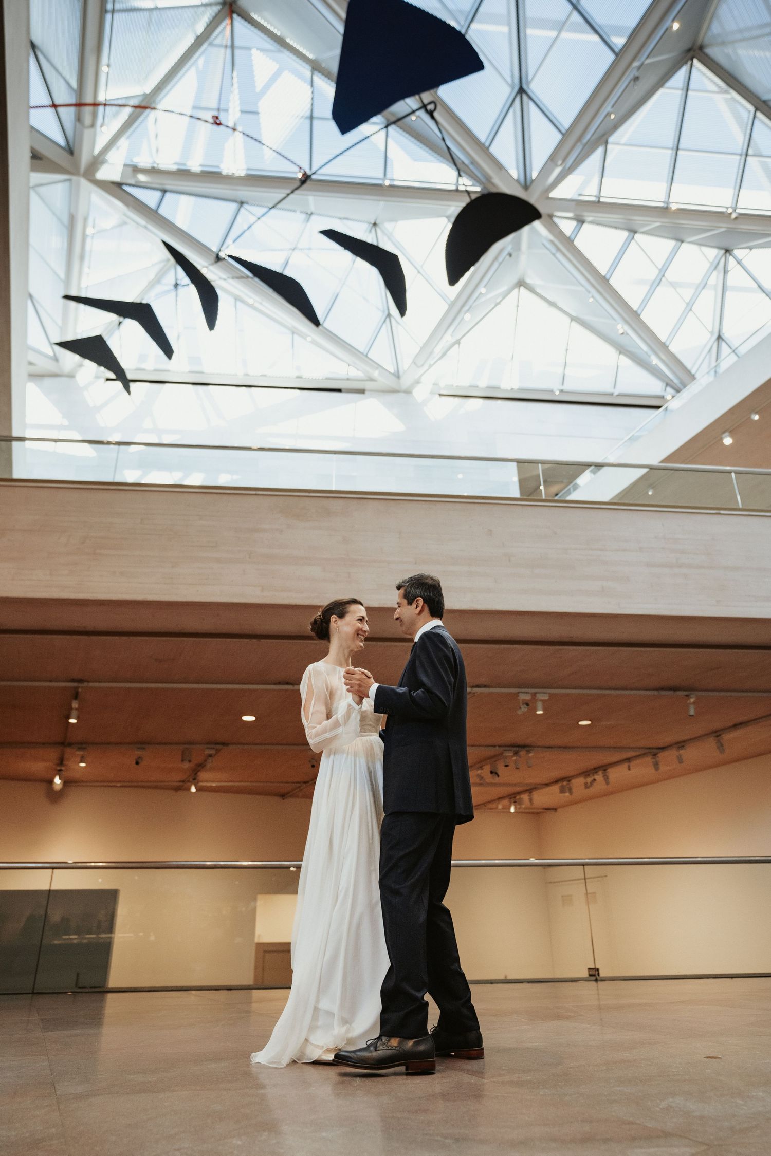 A Washington DC bride and groom sway sweetly below the hanging Calder sculpture at the Smithsonian National Gallery of Art