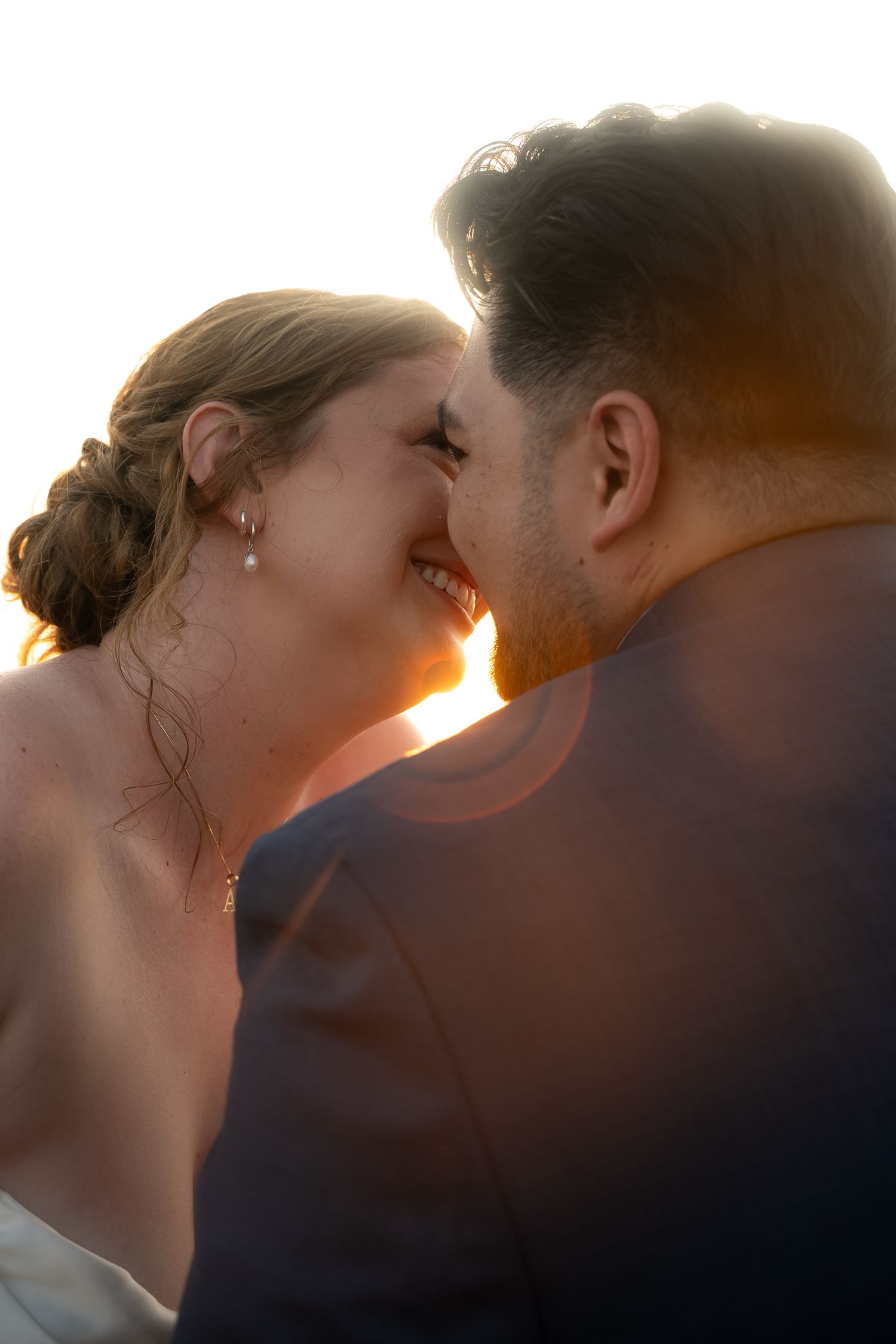 In a Virginia Beach wedding a bride and groom appear as if about to kiss with a light refraction escapes just between their faces