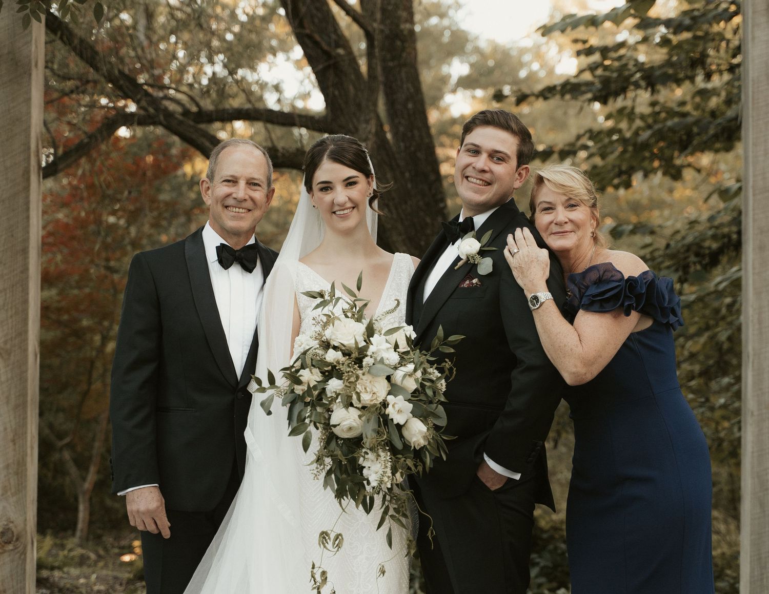 Bride and groom pose for a family portrait with the bride's family after their ceremony during a wedding at Mill at Fine Creek
