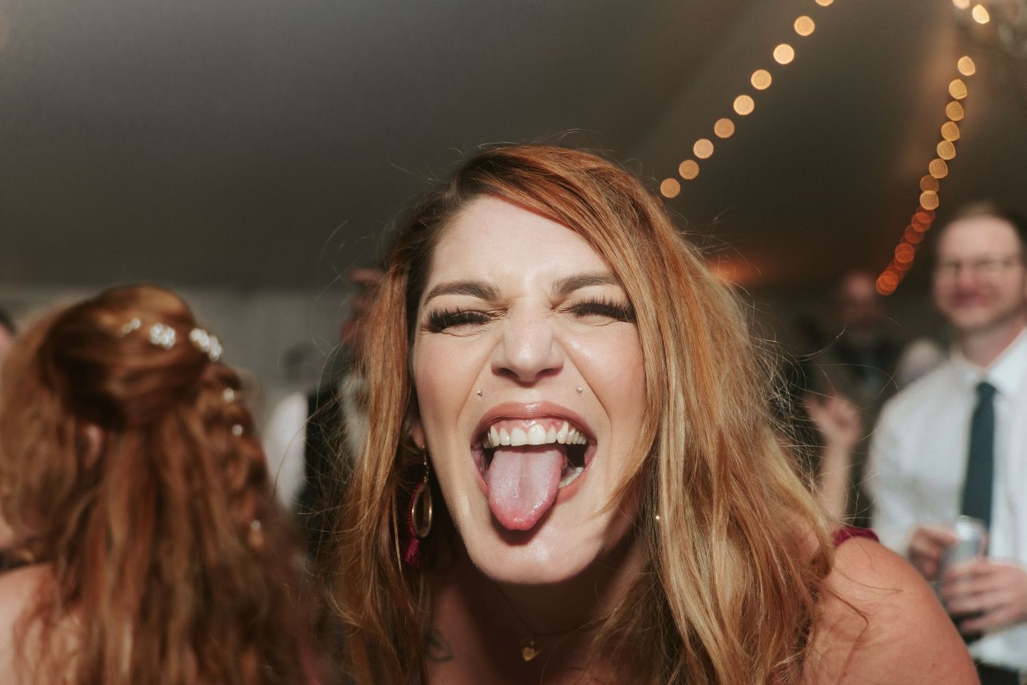 A bridesmaid sticks her tongue out at the camera during the dance party of a wedding reception at Mankin Mansion outside Richmond Virginia