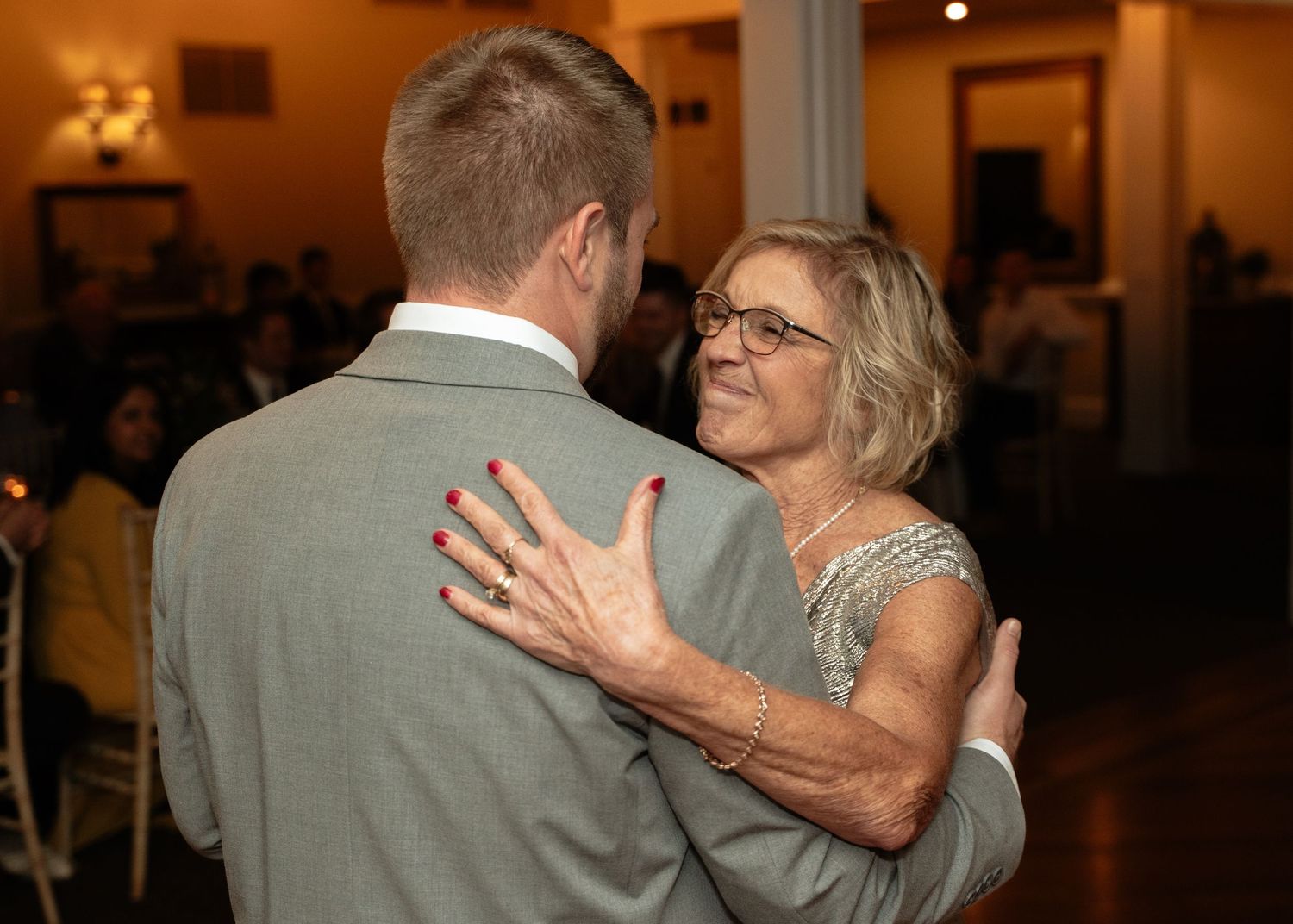 Mother of groom smiles at her son during their mother daughter dance at the Mill at Fine Creek outside Richmond Virginia