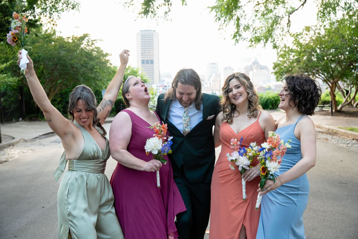 Richmond Virginia bridesmaids pose with the groom in front of the skyline in Church Hill after the ceremony