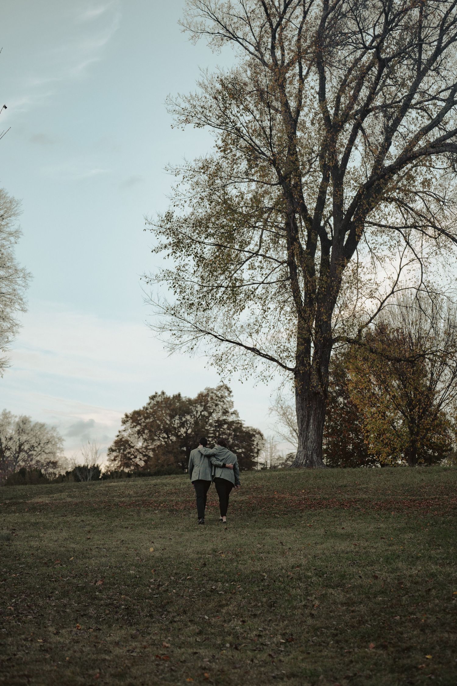 Two lgbtq grooms walk up a hill away from their wedding ceremony at Maymont Park in Richmond Virginia in documentary style photograph