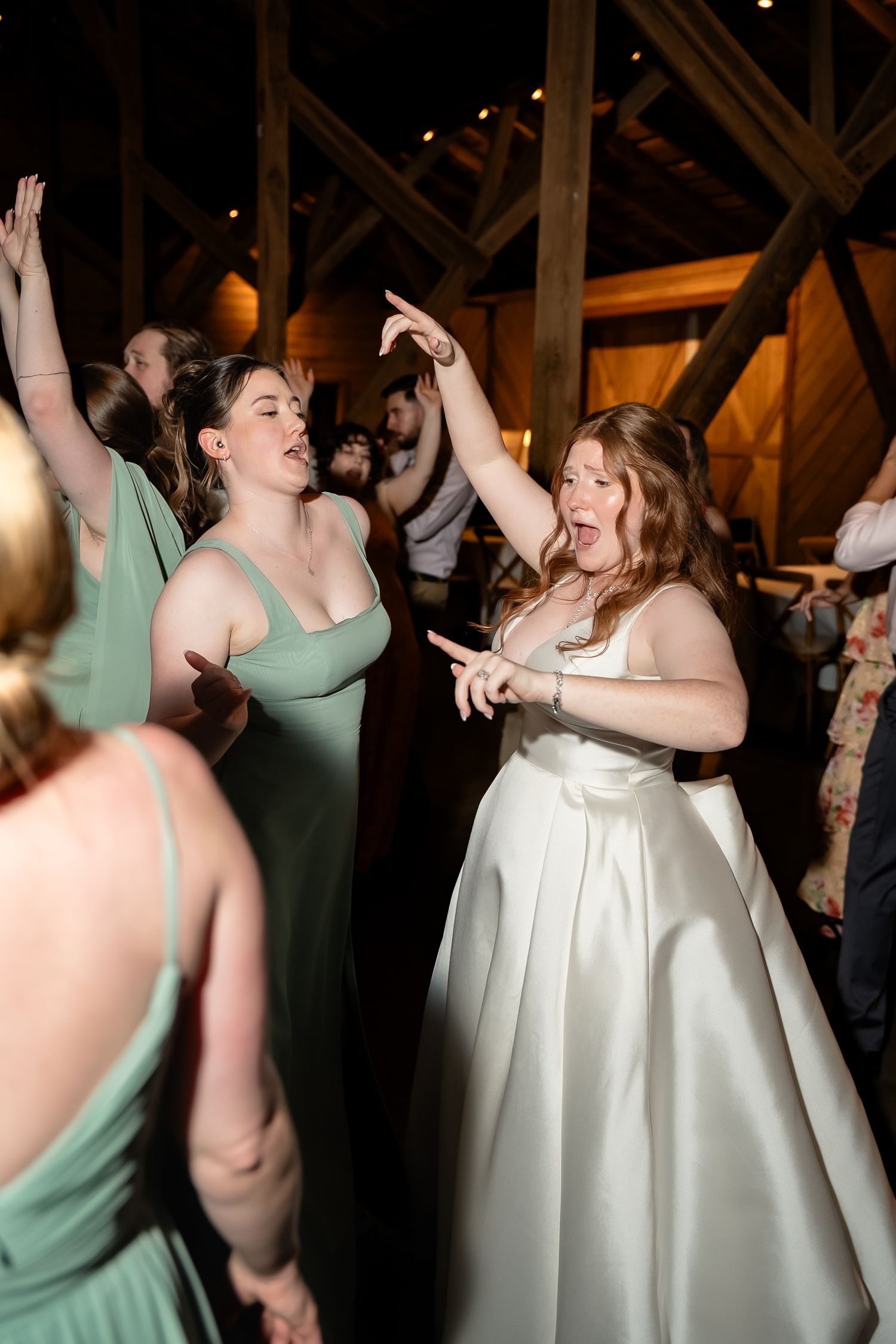 In playful chic documentary style dance party reception bride dances and sings along to music with bridal party dancing next to her