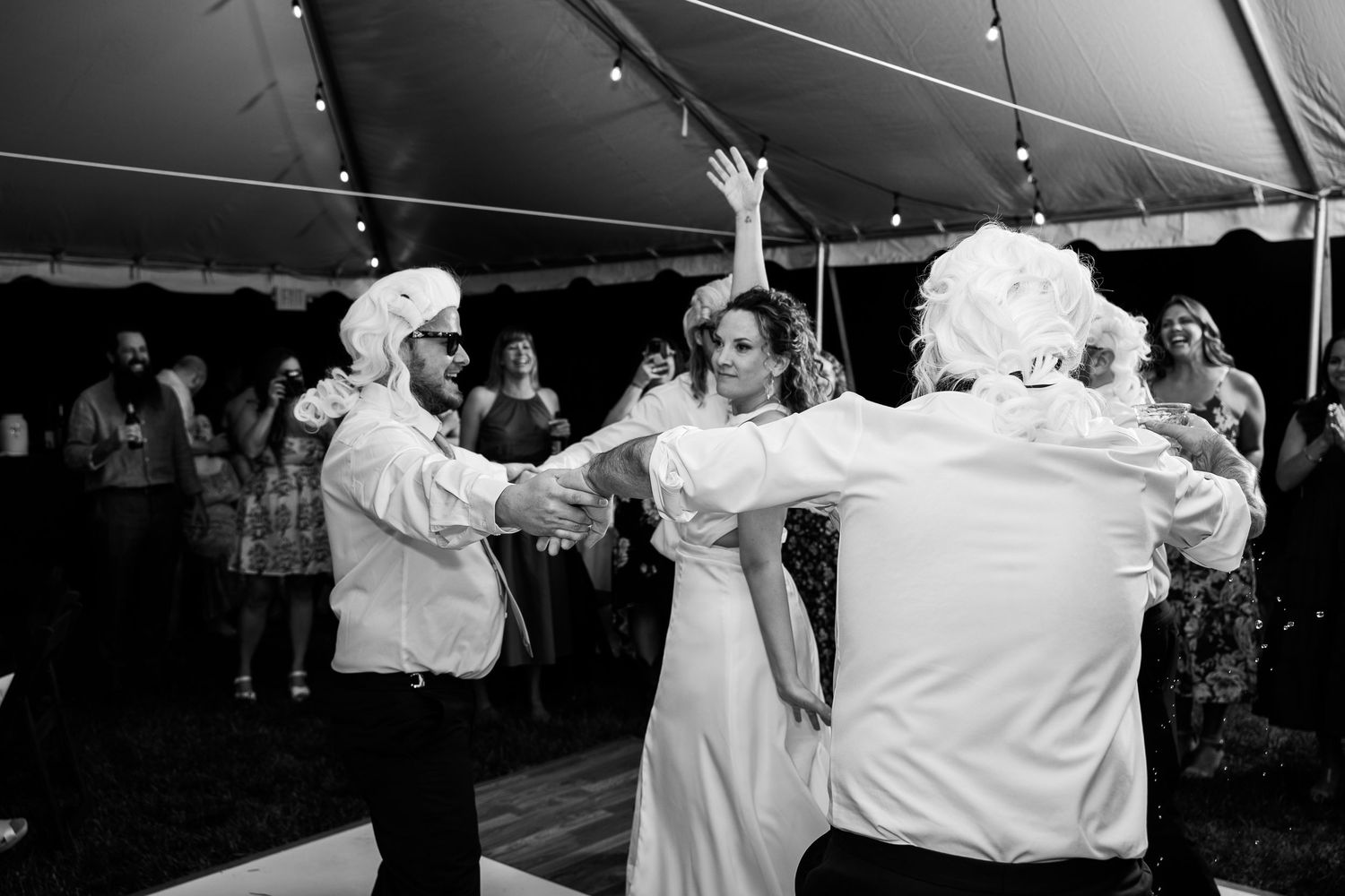 Bride spins on the dancefloor of a tent while surrounded by groomsmen in colonial wigs under a tent in Richmond, Virginia