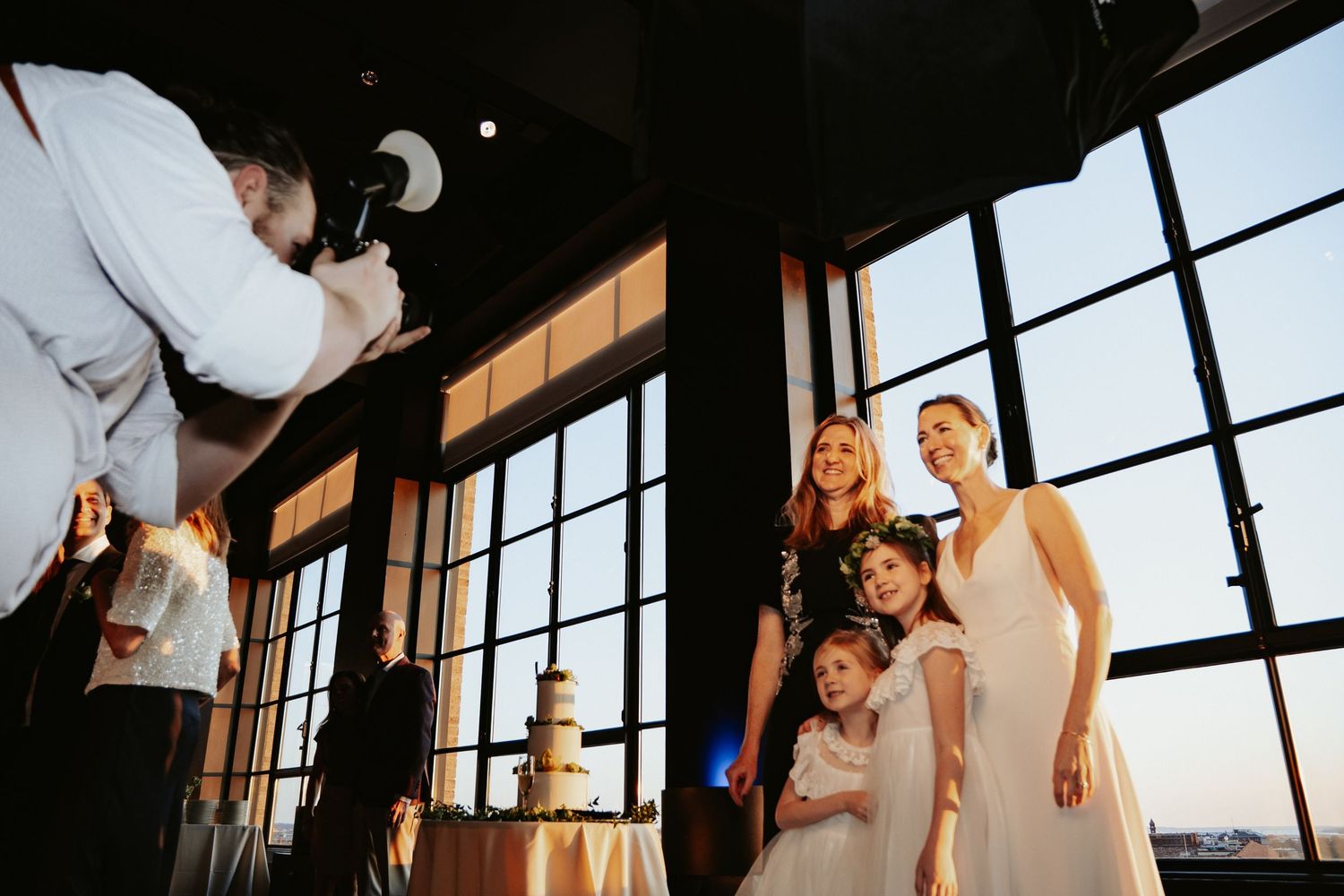 Maine-based wedding and event photographer Dan Bowler takes photo of family in industrial loft wedding venue with large windows and cake