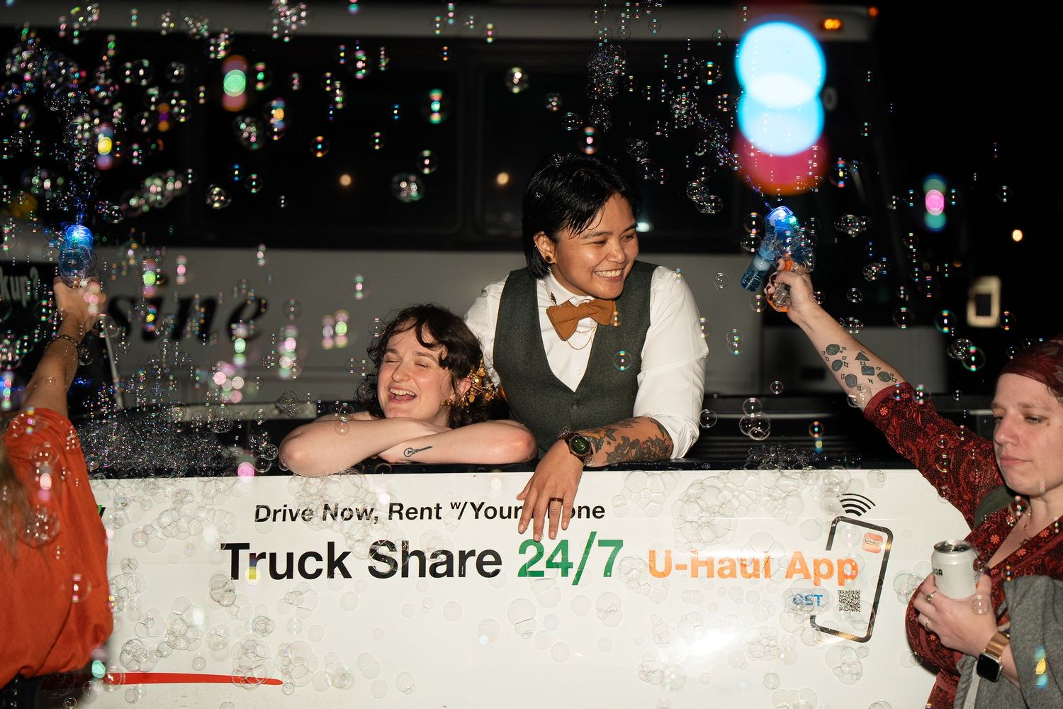 Queer wedding with lesbian couple pose in classic lesbian U-haul photo with bubble send-off in documentary style wedding photo session