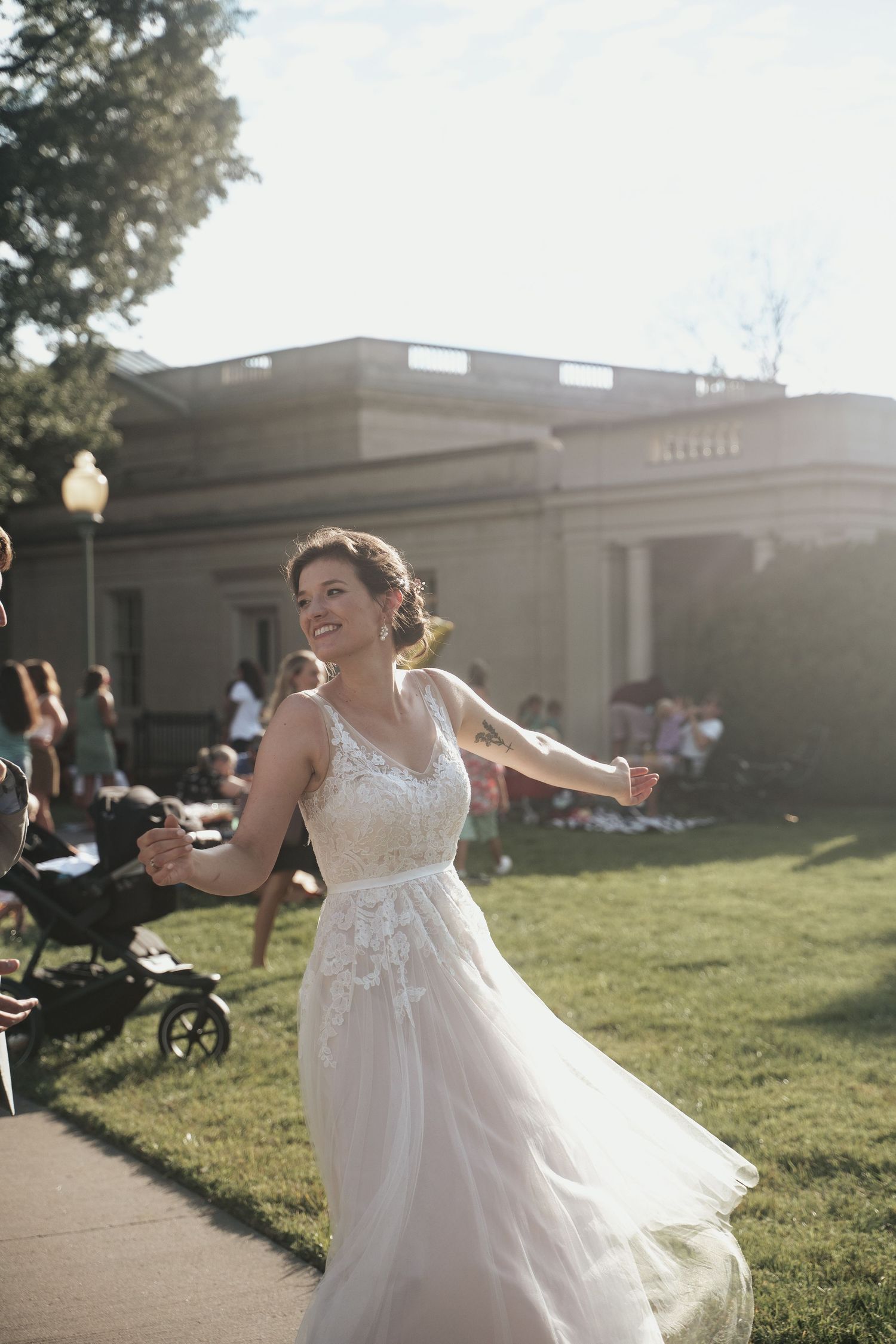 Bride in a flowing white wedding dress spins out of her groom's arms in the courtyard of the Virginia Museum of Fine Arts