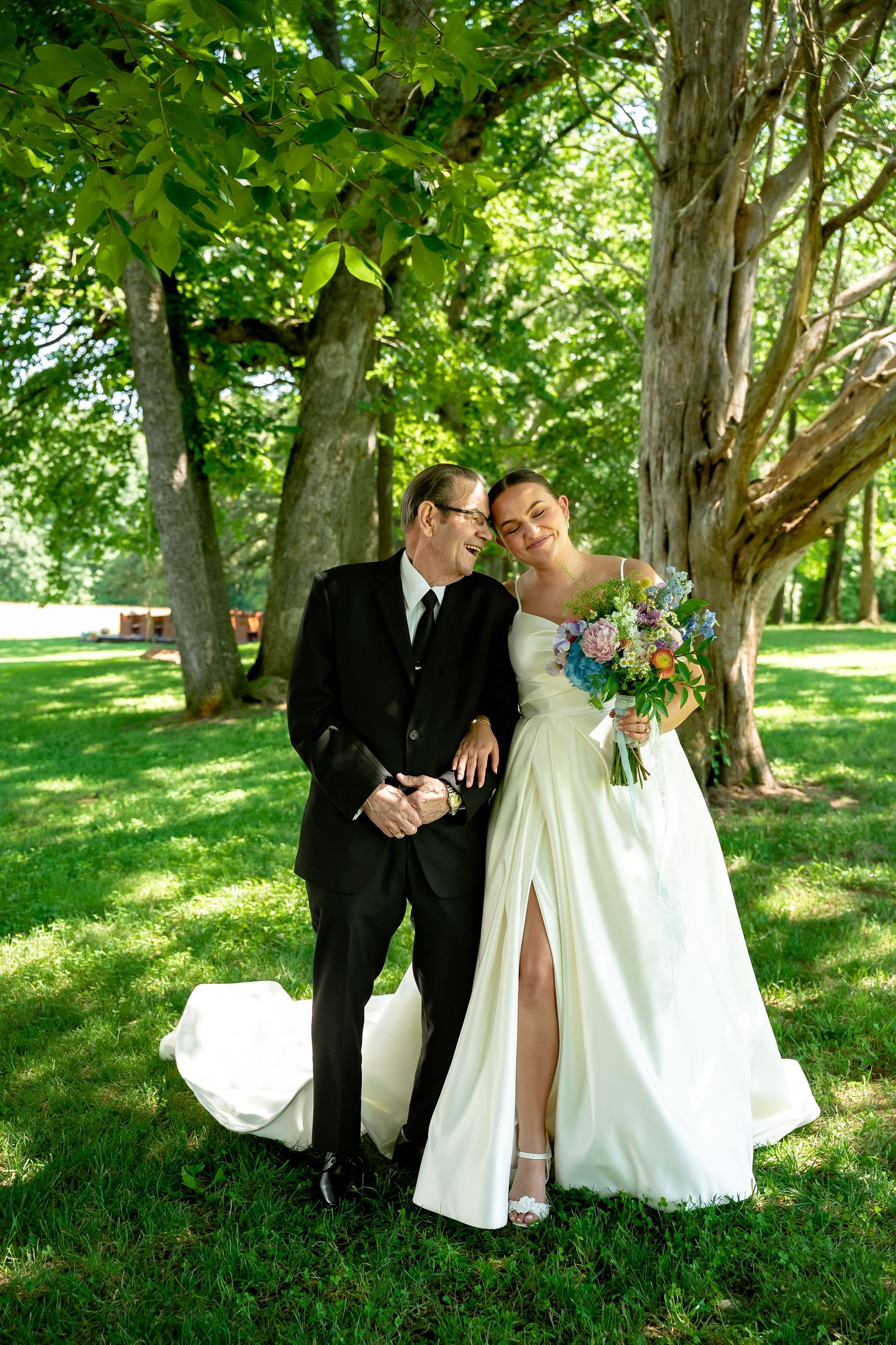 Father of bride laughs with her in a flowing timeless wedding dress at a breezy wedding on Avonlea Farms outside Richmond Virginia